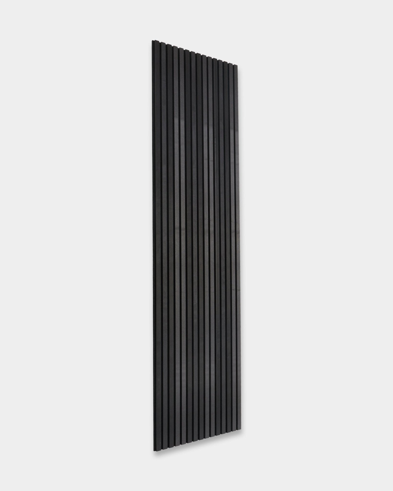 WoodUpp Akupanel Tonal Panneau acoustique en frêne Black (300 x 60 cm), avec des lattes vertical, installé sur un mur uni gris clair, dans un style scandinave minimaliste.