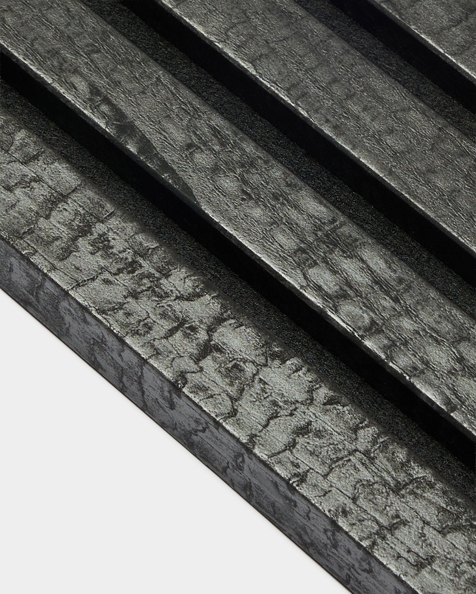 Lamelle de finition WoodUpp Akupanel en Charcoal (2,2 cm), avec des panneaux acoustiques en bois texturés et posés en diagonale, dans une finition charbonnée black, pour une installation murale.