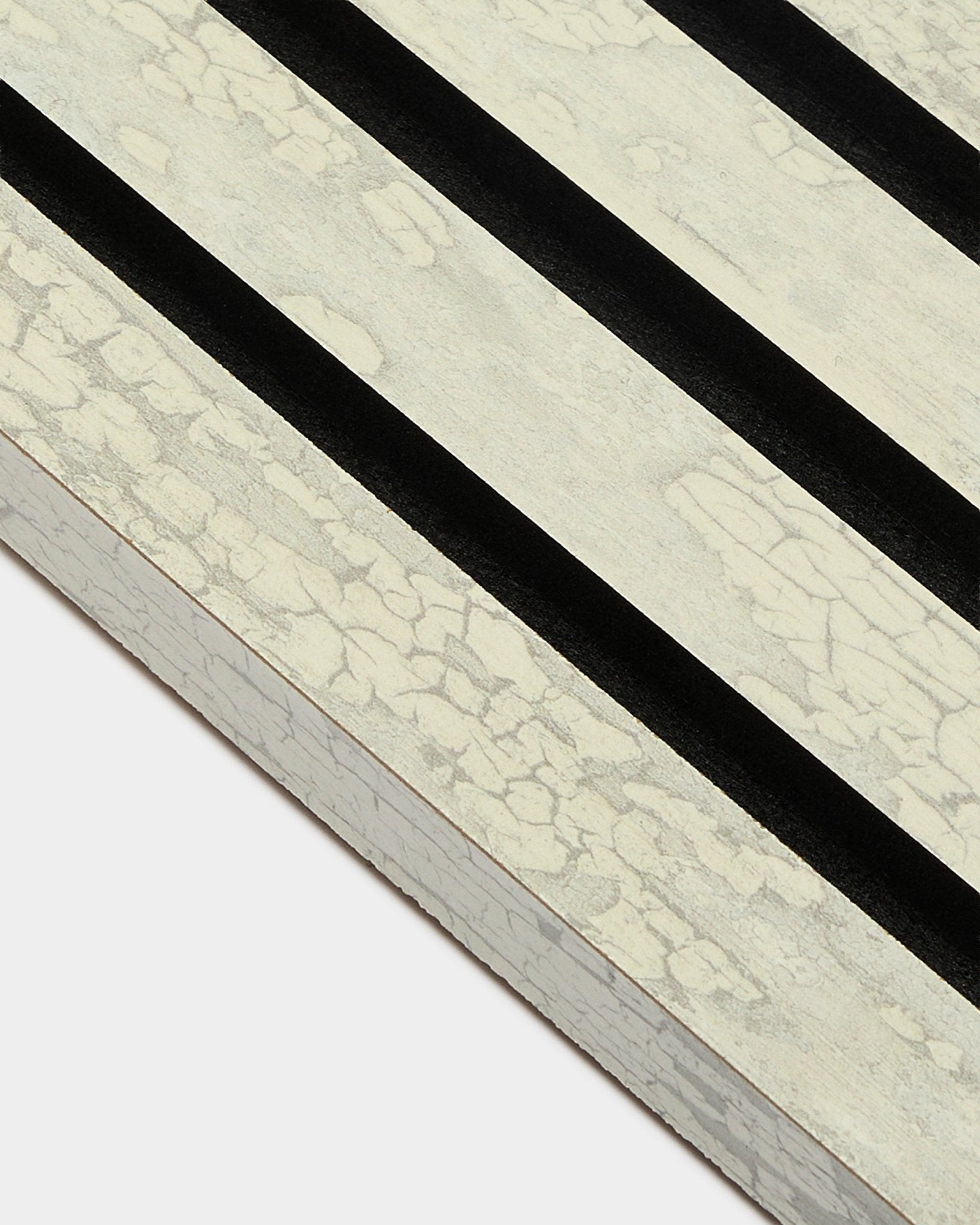Gros plan sur la lamelle de finition WoodUpp Akupanel en Oxide White (2,2 cm), avec trois bandes diagonales black sur un cadre MDF Panneau acoustique.