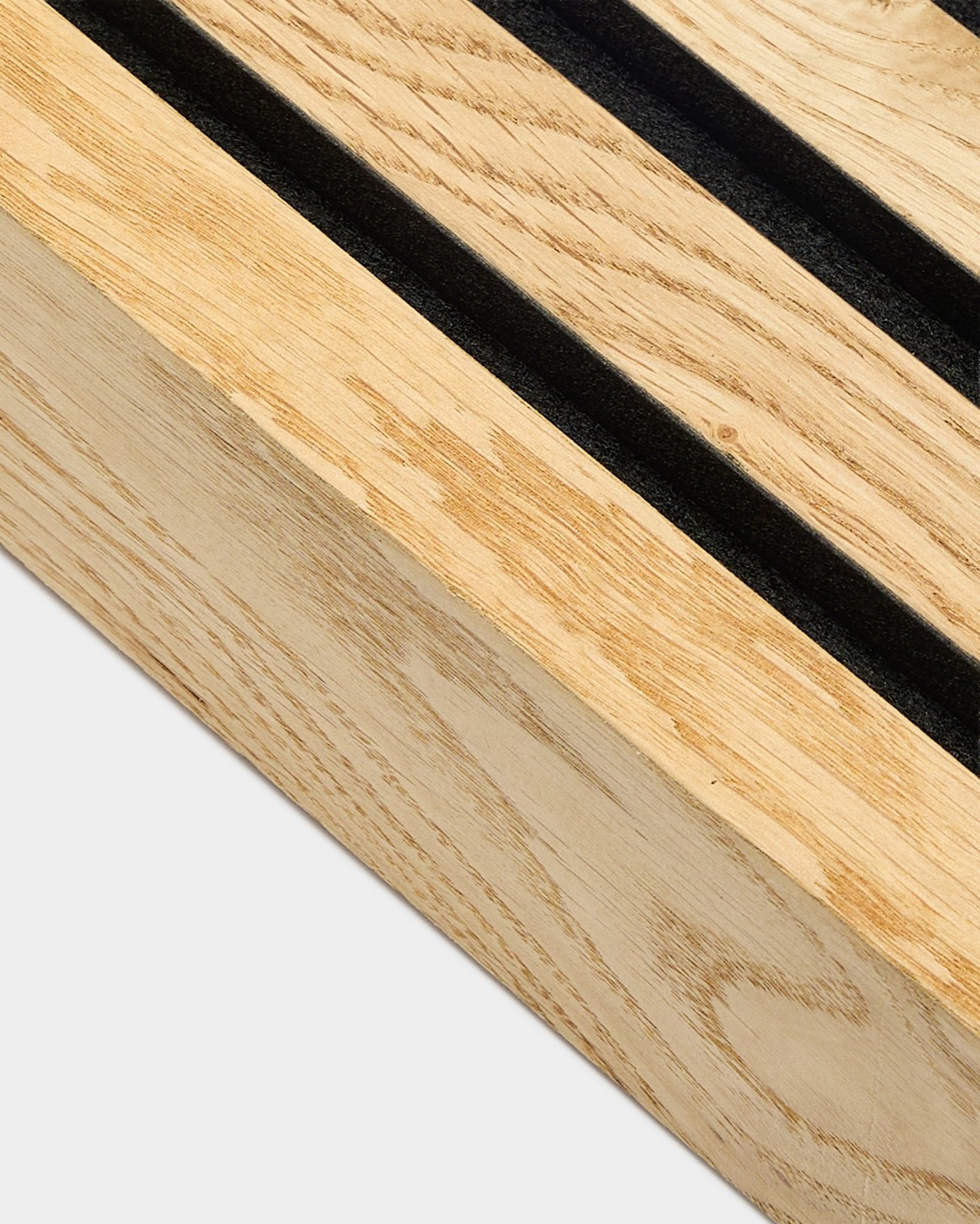 Gros plan sur une lamelle d’extrémité WoodUpp Akupanel en Rustic Natural Oak, 6,7 cm, avec des rainures parallèles black et un cadre en MDF pour une installation murale acoustique.
