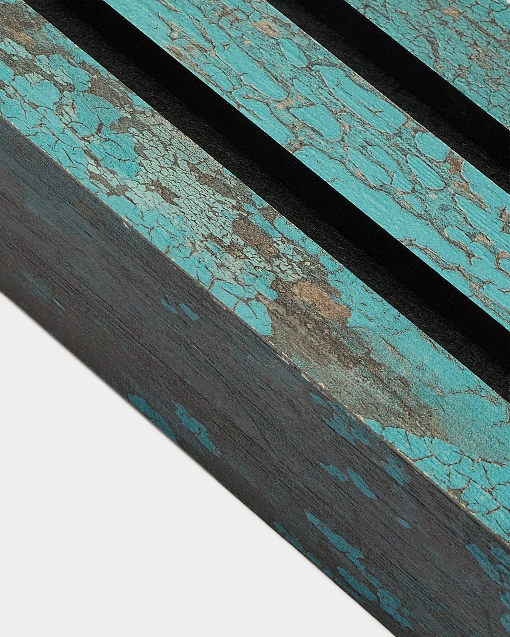Gros plan sur la lamelle de finition WoodUpp Akupanel en Oxide Blue, largeur 6,7 cm, avec peinture bleue craquelée et rainures black sur une surface Panneau acoustique rustique.