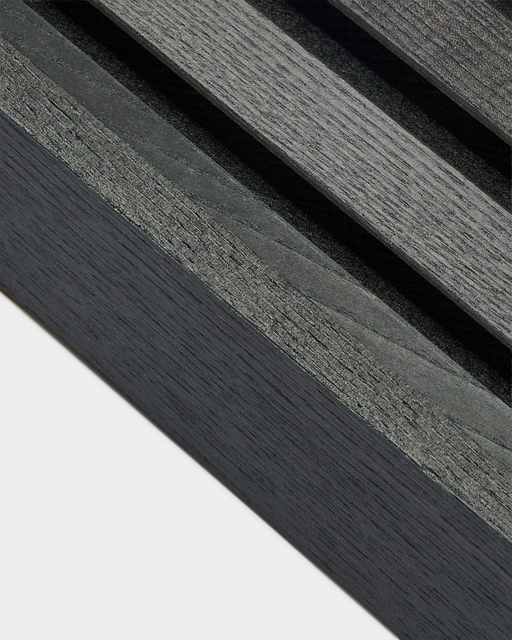 Gros plan sur la lamelle d’extrémité WoodUpp Akupanel en frêne Black (6,7 cm), montrant un veinage bois gris foncé sur une base claire, conçue pour les installations nordiques Panneau acoustique.