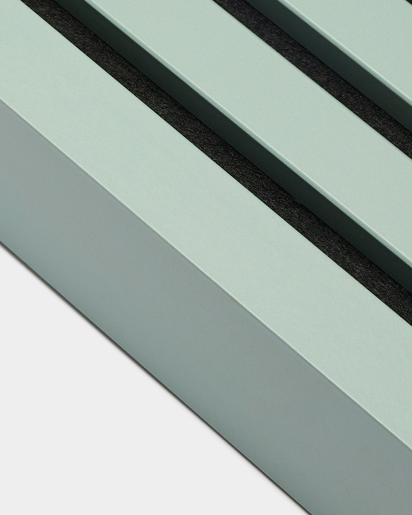 Gros plan sur l’accessoire d’installation WoodUpp Akupanel : lamelle de finition en Cloud, largeur 6,7 cm, cadre en MDF vert menthe avec deux rainures black, sur fond blanc.