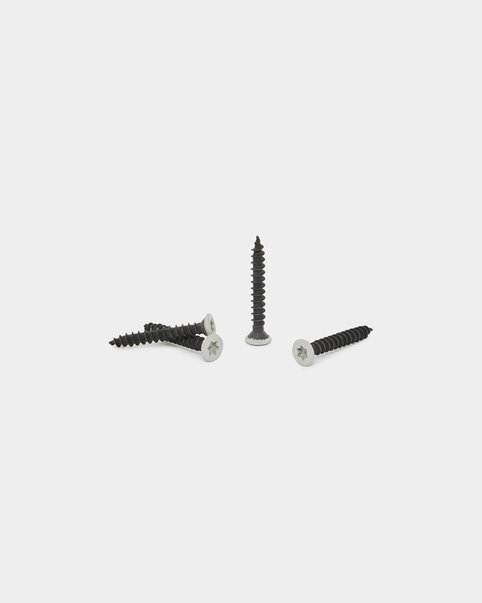 Quatre vis WoodUpp grey du kit de produits d’installation (100 pcs), présentées sur un fond blanc uni ; trois sont horizontal et une est placée à la verticale.