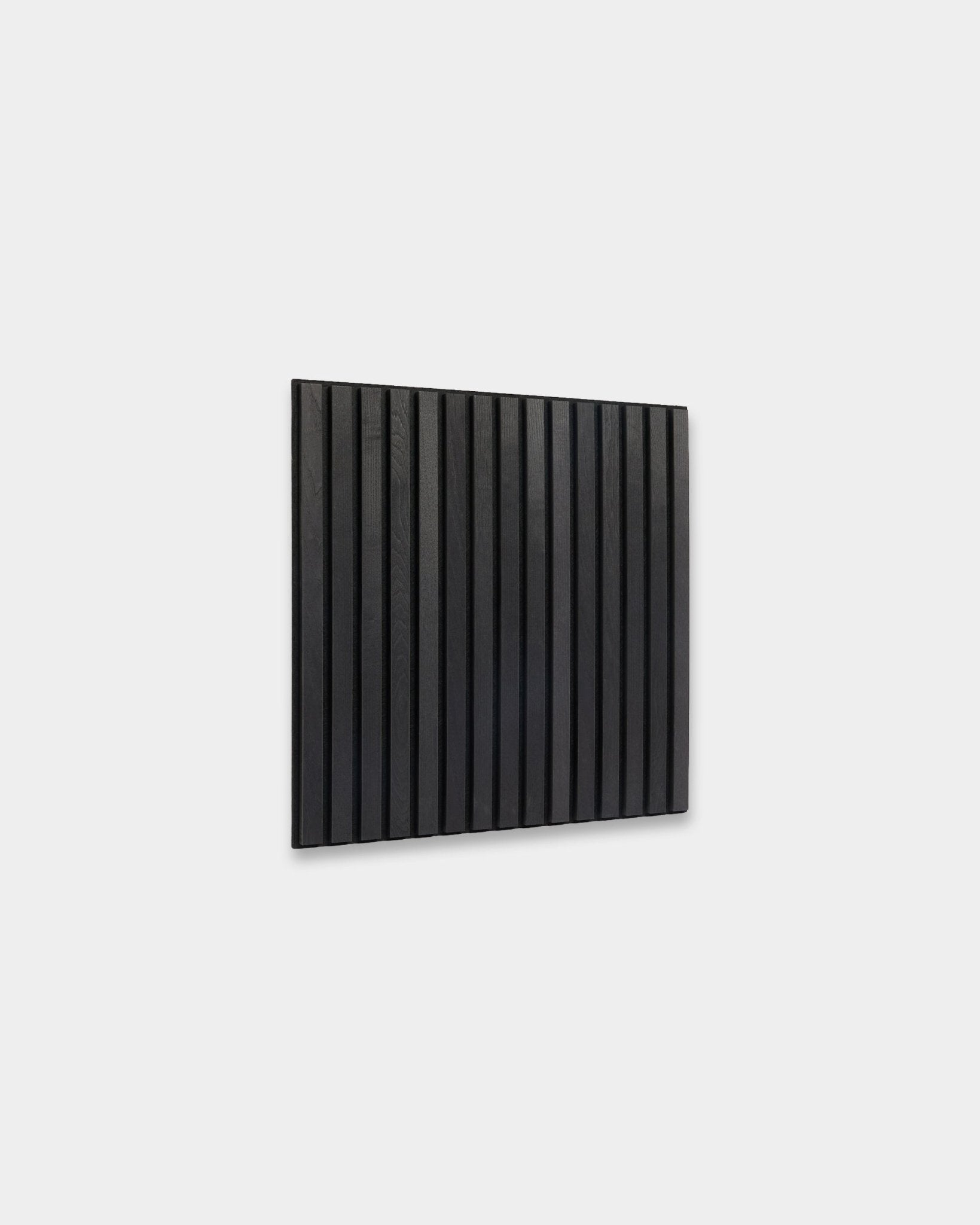 WoodUpp Akupixel Black Ash Panneau acoustique (60x60 cm) avec des lattes en bois vertical, fixées sur un mur gris clair, dans un style scandinave minimaliste.