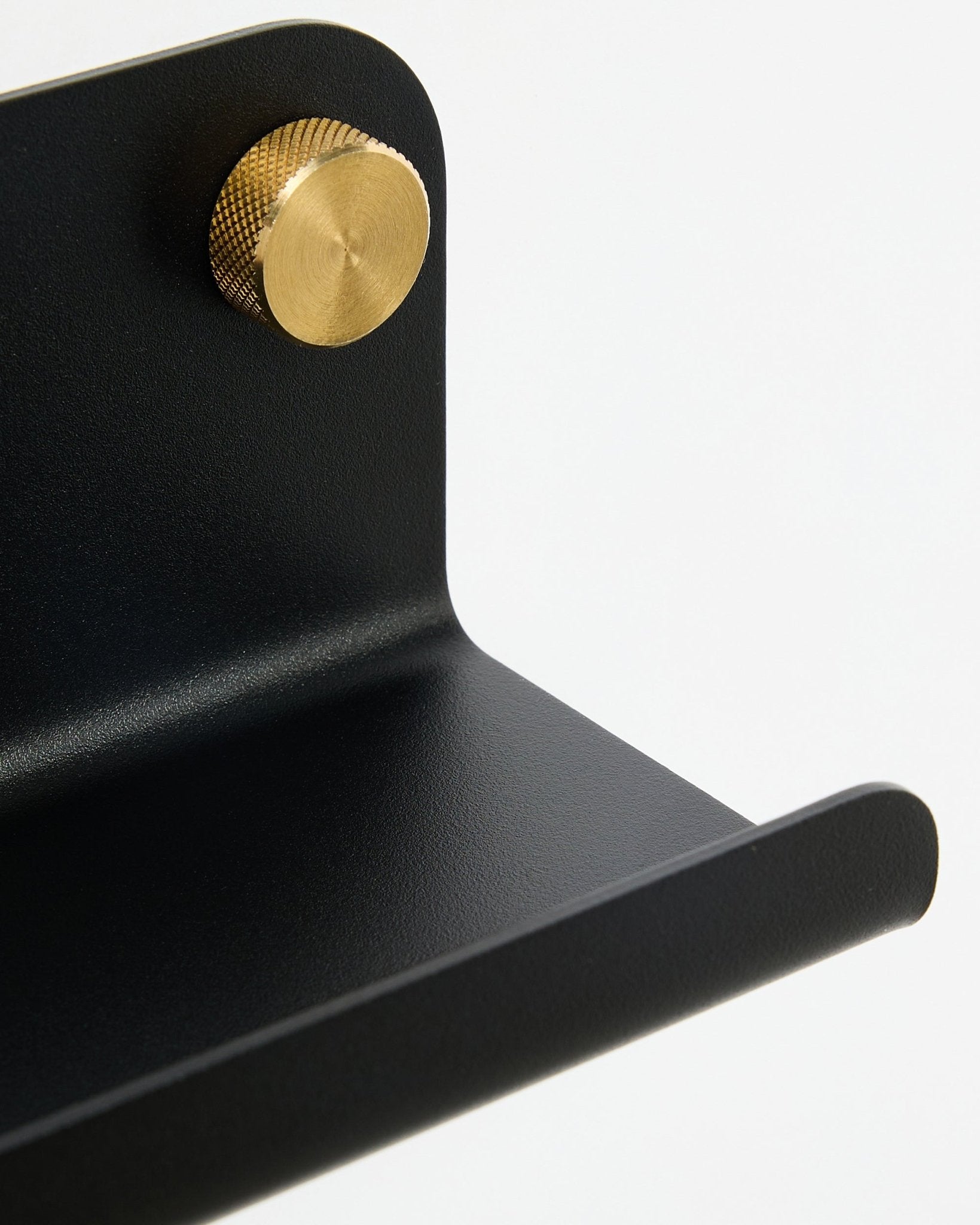 Gros plan sur l’étagère étroite WoodUpp Norr, 35,9 cm, black steel avec bord incurvé et bouton doré, sur fond blanc.