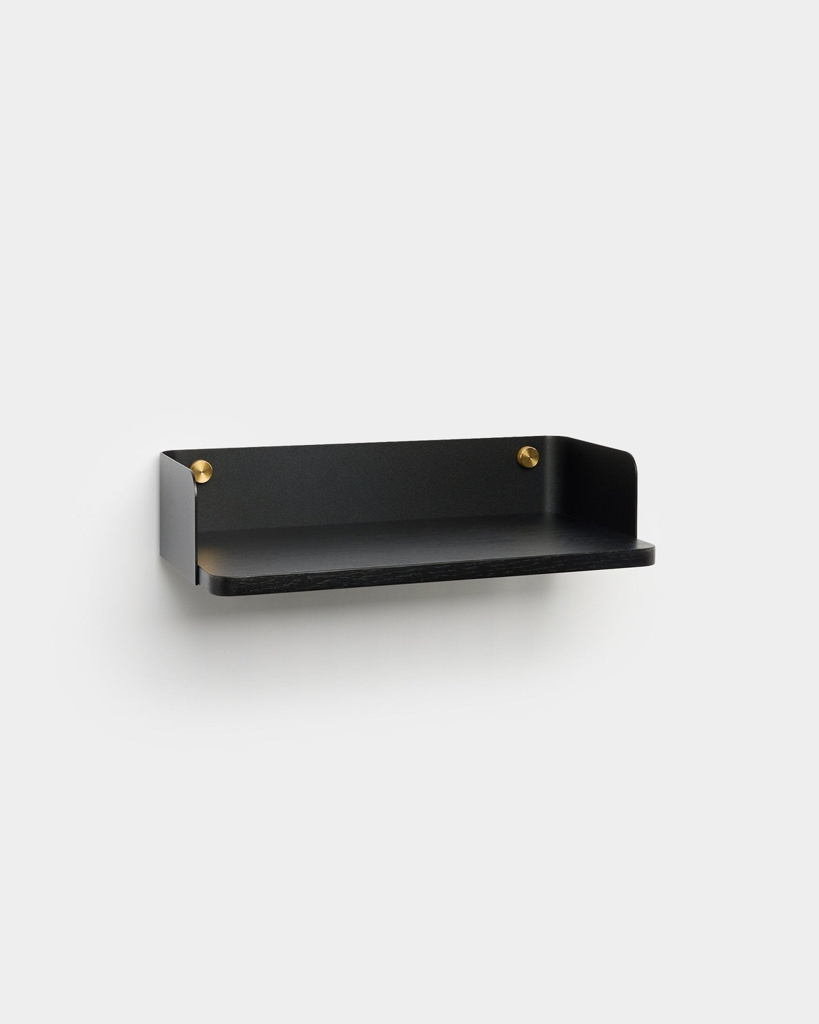 L’étagère Linn de WoodUpp, dans une finition minimaliste black avec des vis de fixation brass, est installée sur un mur gris clair et s’accorde avec un intérieur au style nordique.