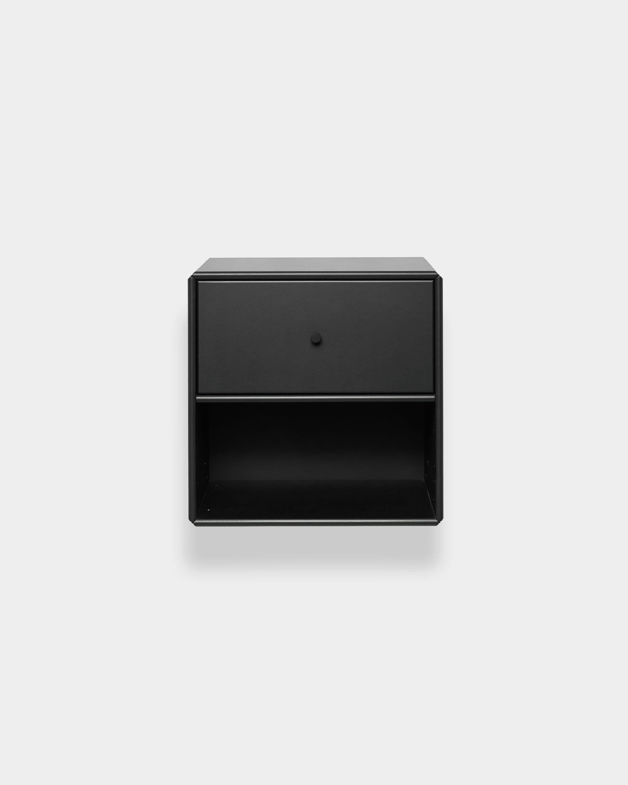Bibliothèque WoodUpp Arka noire, dotée d’un tiroir et d’une étagère ouverte, sur fond gris clair. Design minimaliste nordique.