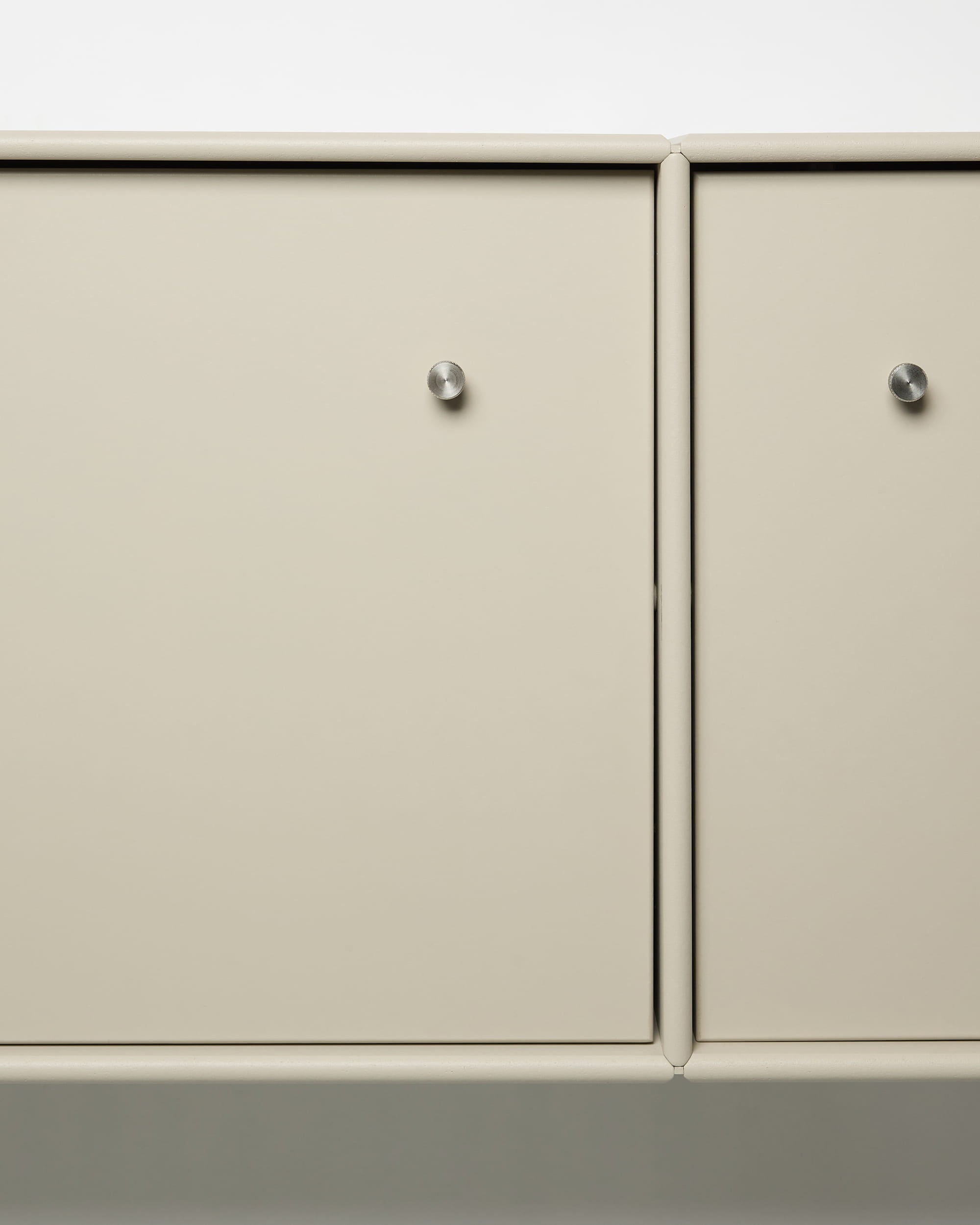 Meuble TV Arka de WoodUpp, avec des portes en métal beige, des poignées rondes argentées, une conception modulaire et un système de rangement des câbles intégré, idéal pour les intérieurs nordiques.