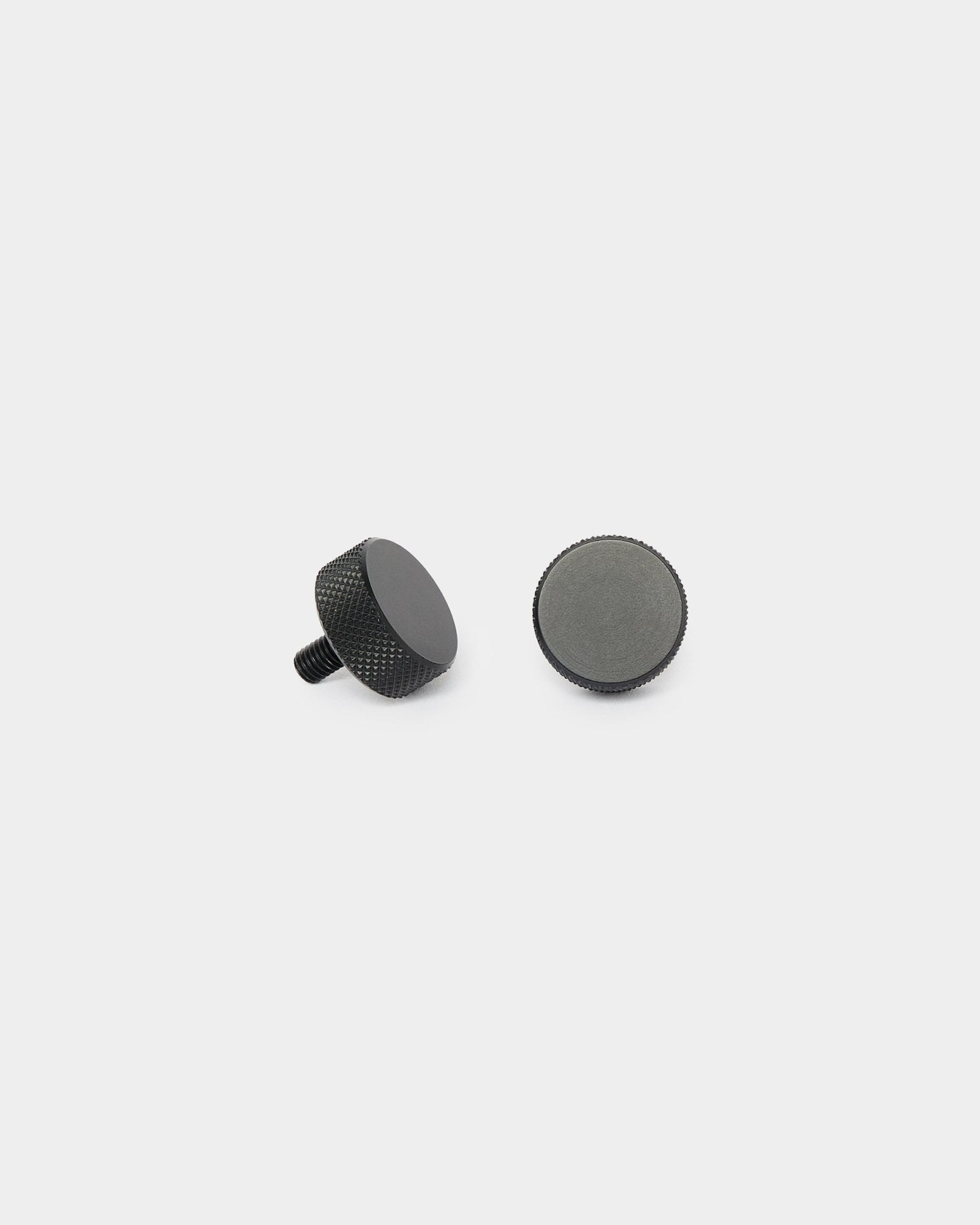 Deux vis WoodUpp Finger black (2 pcs, M5x10mm, 20x8.8), présentées debout et couchées sur un fond blanc uni pour l’installation de Akupanel.