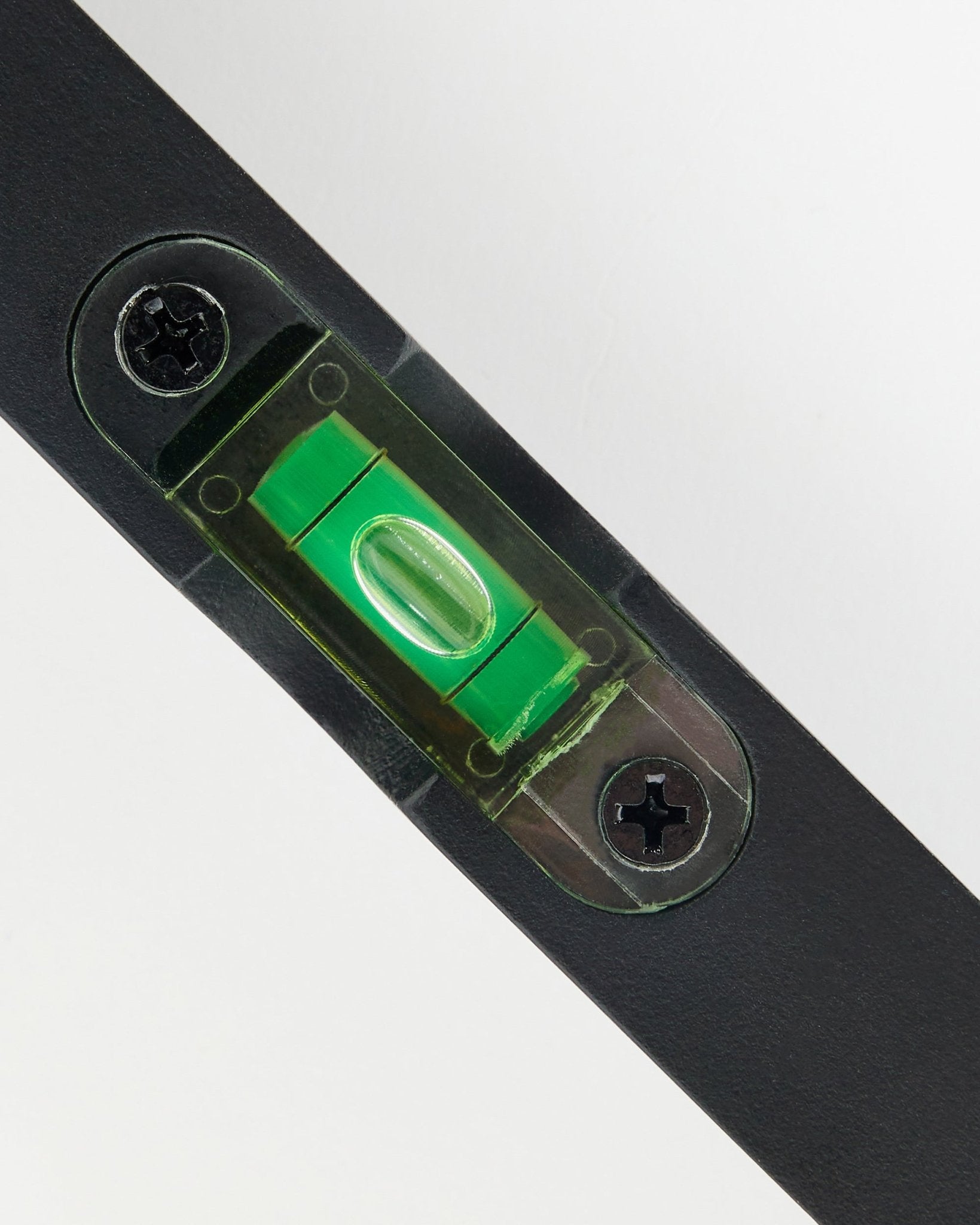 Gros plan sur un niveau à bulle black WoodUpp (15 x 3,2 cm) avec fiole verte, utilisé pour l’installation précise de panneaux acoustiques.