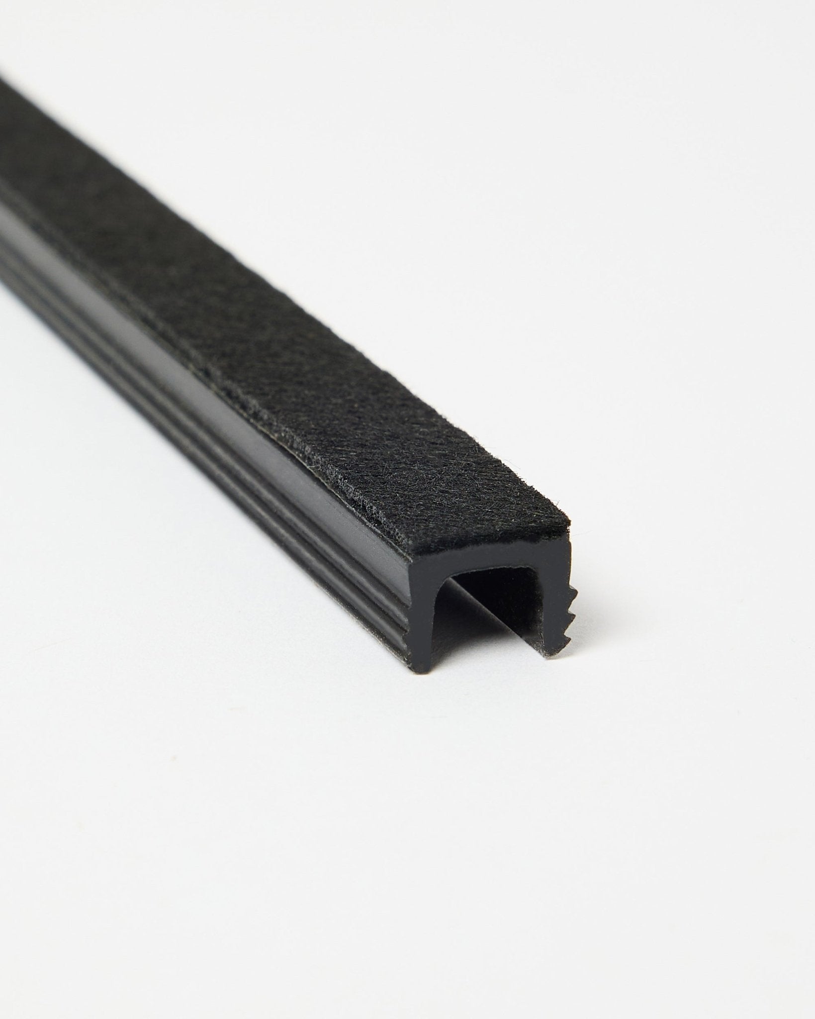 Trois cache-câbles Pop-on black Dupps de WoodUpp, présentés en biais sur un fond blanc pour mettre en valeur leur forme et leur finition. Accessoires pour les systèmes Akupanel.
