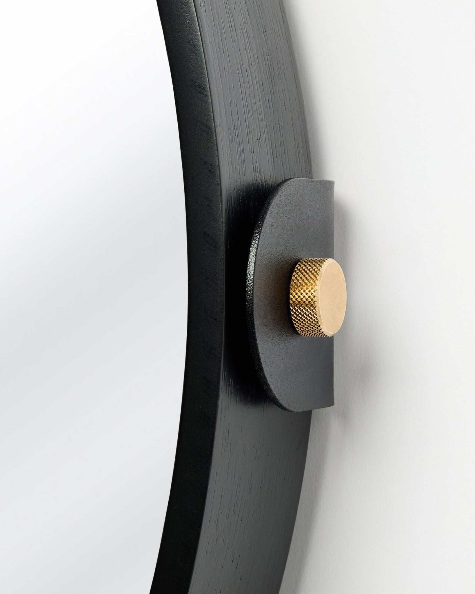 Détail du Linn | Mirror / Black Oak Panneau acoustique de WoodUpp, fixé au mur avec un bouton doré et une inclinaison réglable.