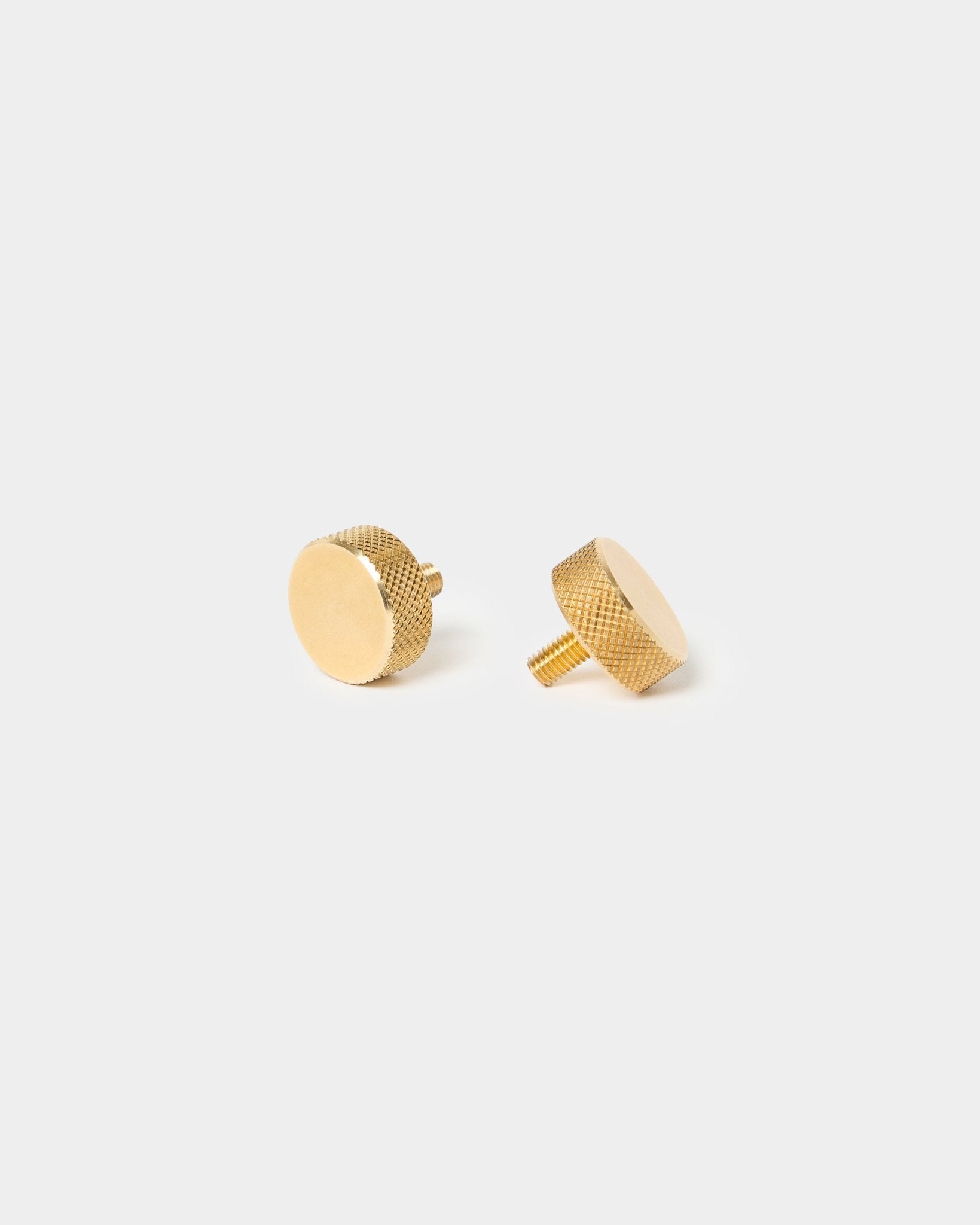 Paire de vis moletées WoodUpp brass (M5x10 mm, 20x8.8), avec bords texturés et tiges courtes, conçues pour les accessoires Akupanel, sur un fond clair uni.