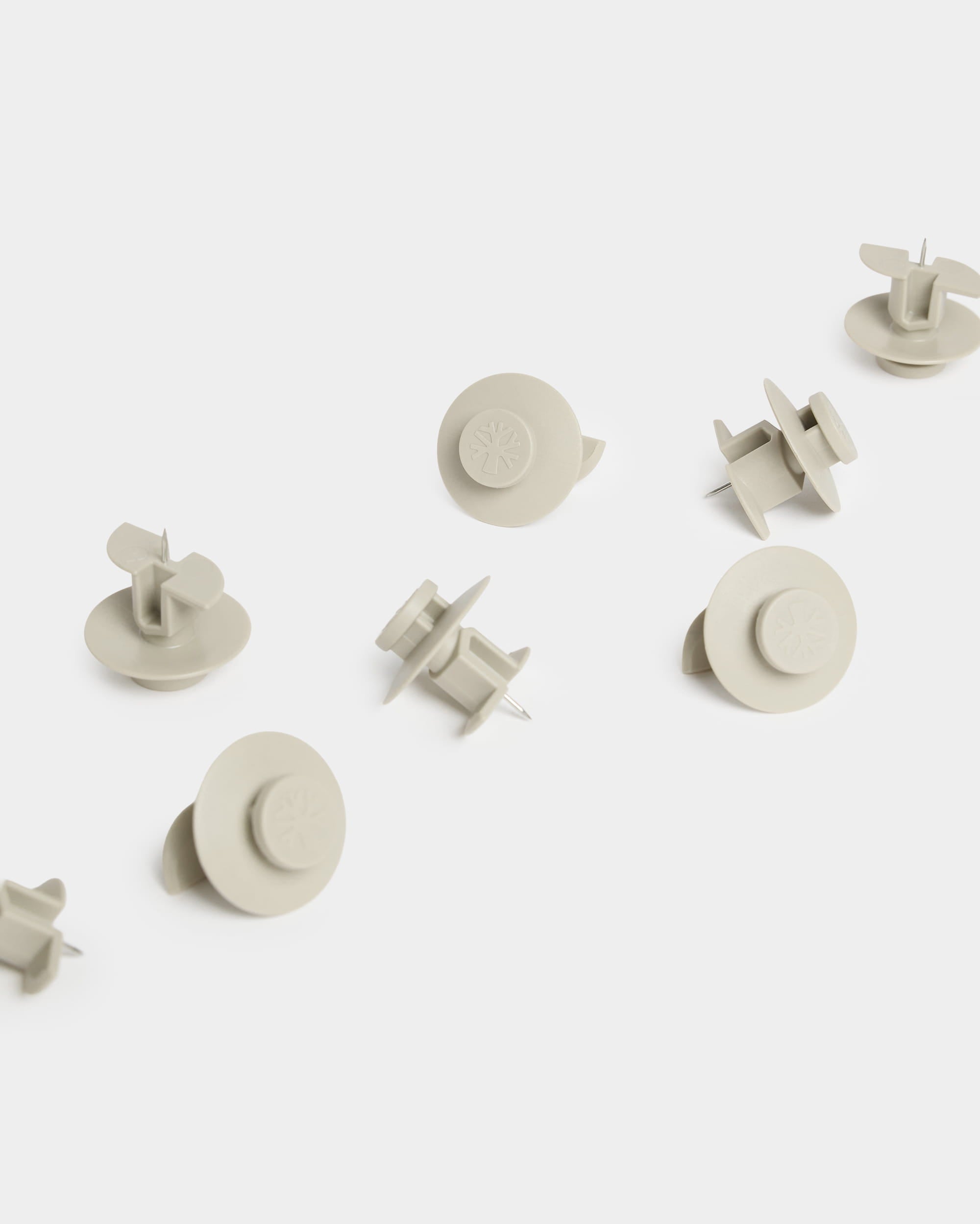 Dix punaises WoodUpp Dupps beiges (modèle « Light ») à tête ronde sont disposées sur une surface blanche ; elles sont conçues pour être utilisées avec des accessoires pour panneaux acoustiques.