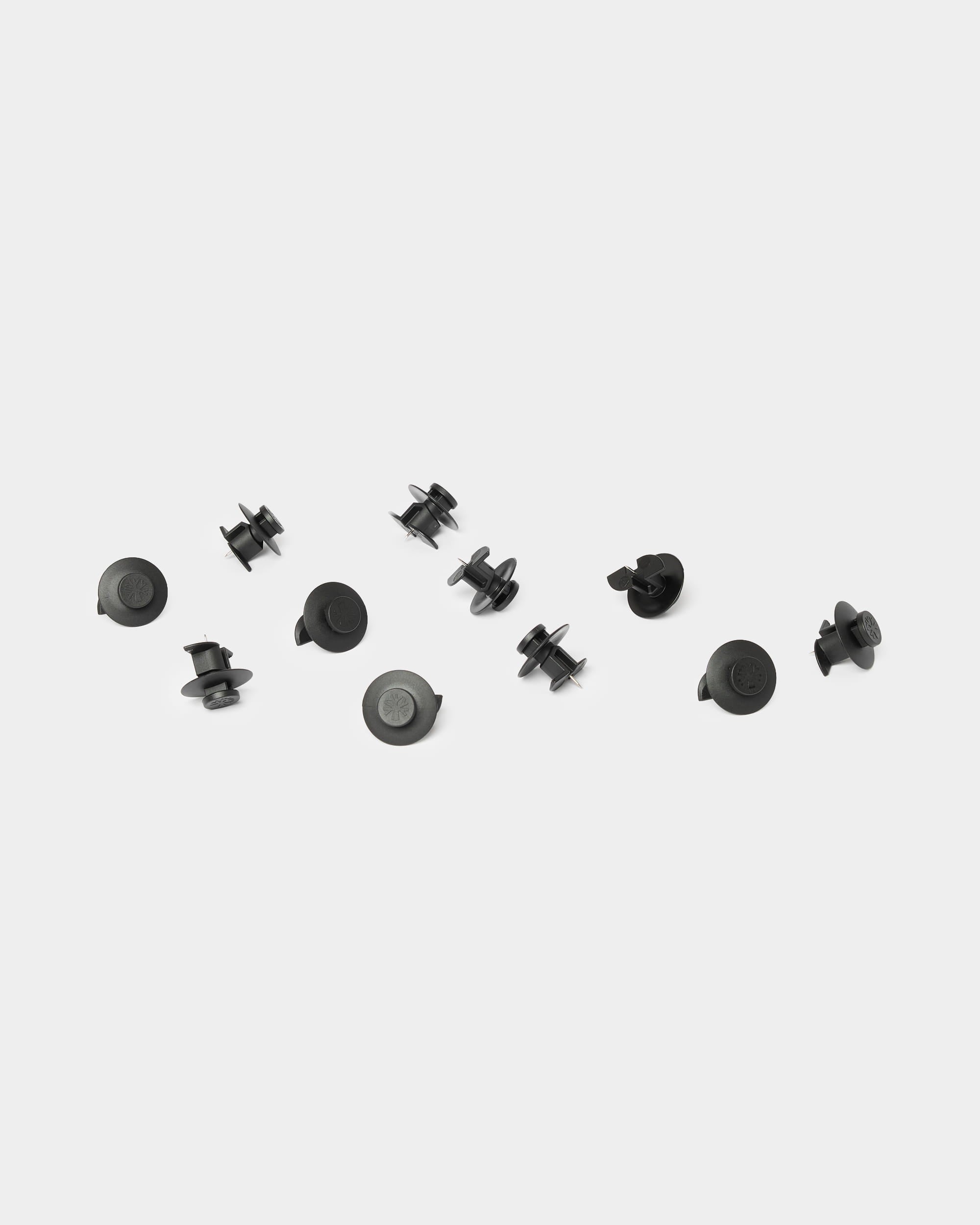 Dix accessoires WoodUpp Dupps de couleur noir clair sont disposés sur un fond blanc uni ; ils sont conçus pour être utilisés avec les panneaux acoustiques en bois Akupanel.