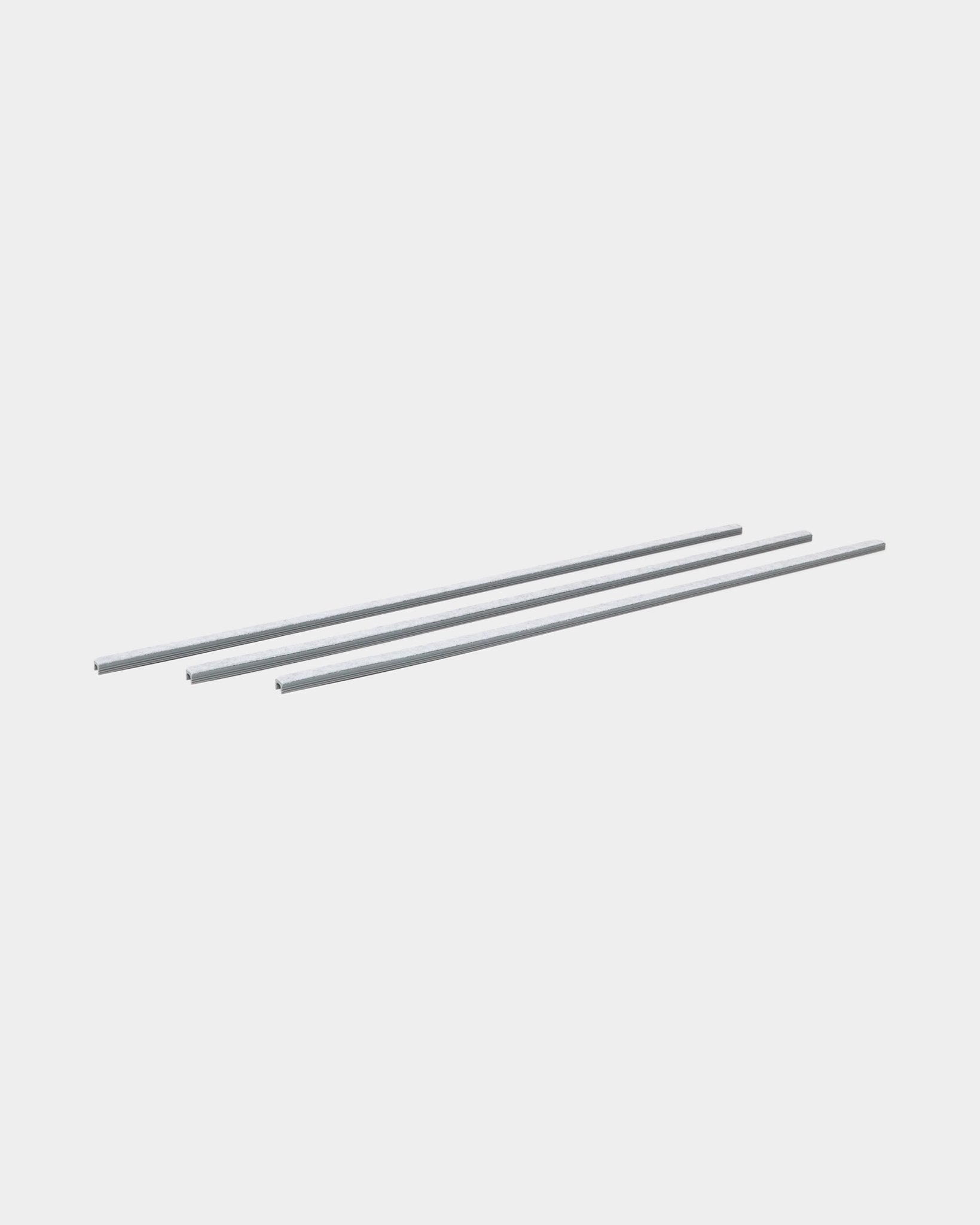 Trois grey Dupps cache-câbles Pop-on (3 pcs) de WoodUpp sont alignés parallèlement, conçus pour organiser les câbles avec les panneaux acoustiques en bois Akupanel.
