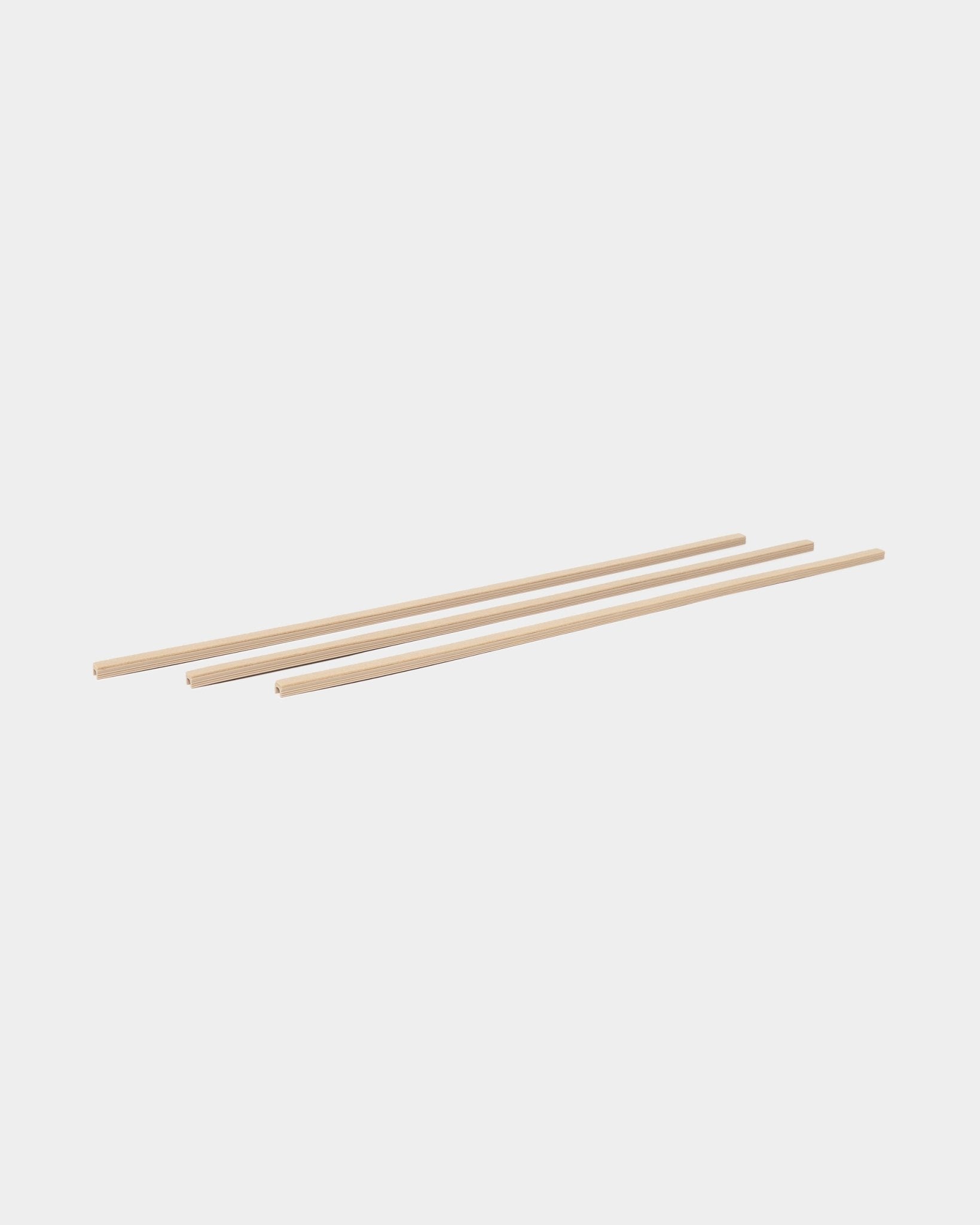Trois cache-câbles Pop-on beige Dupps (lot de 3) de WoodUpp, de la collection d’accessoires CREATE, disposés en parallèle sur un fond blanc.