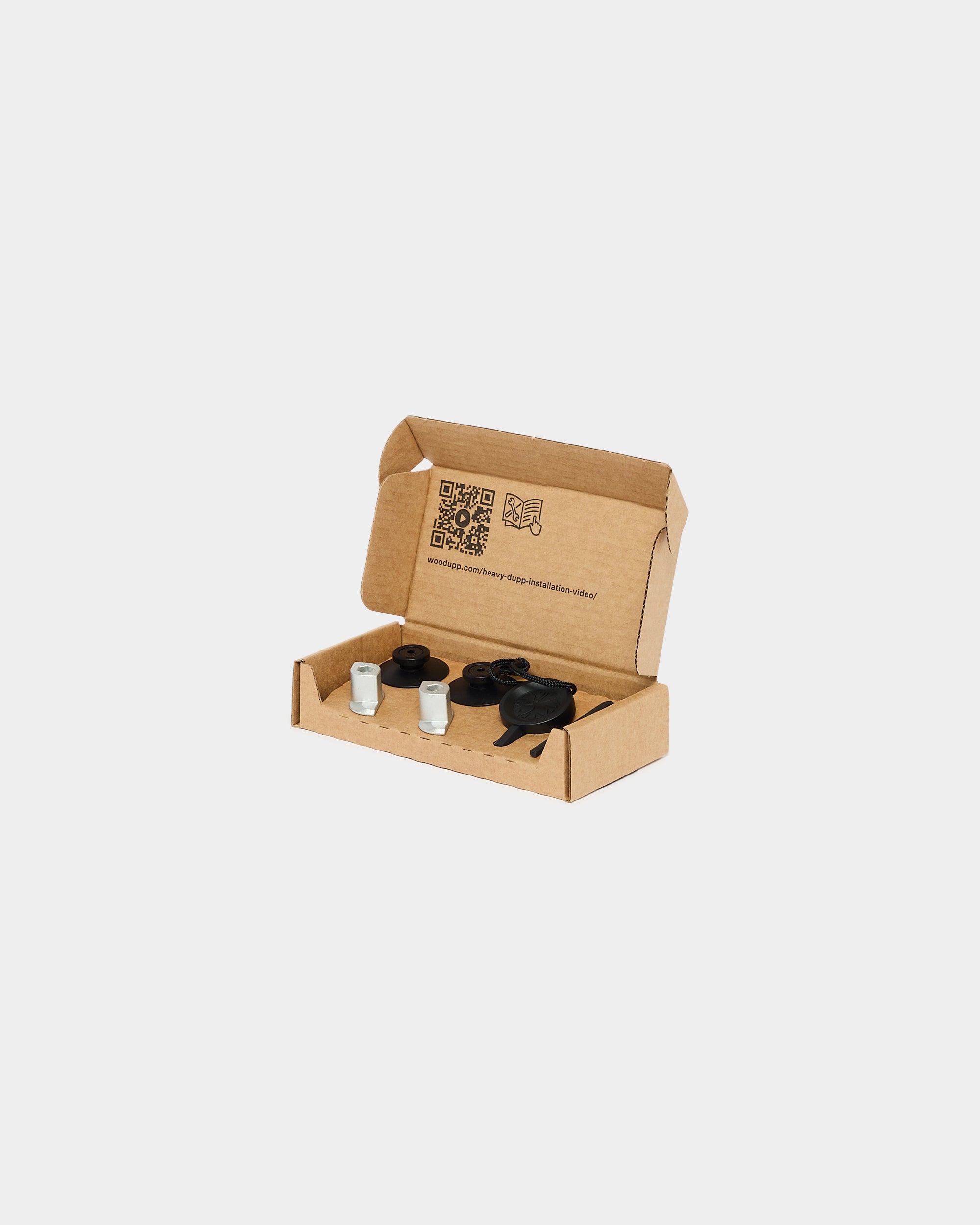 Cardboard box containing two glass vials of white powder and black plastic accessories, intended for precise assembly of acoustic panels, on a white background.