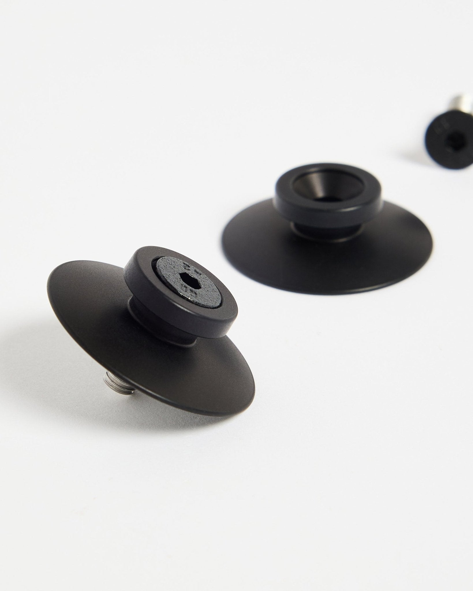 Deux fixations WoodUpp Dupps en aluminium black (2 pcs) sur une surface blanche, conçues pour monter solidement des panneaux acoustiques ou des séparateurs de pièce.