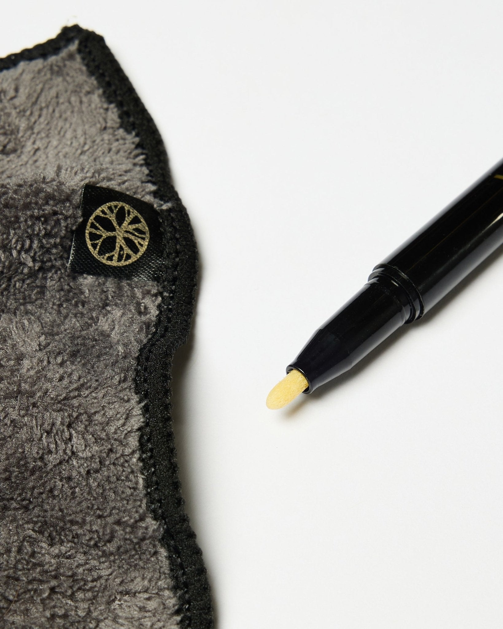 Le set Blackboard Norr de WoodUpp comprend un marqueur à encre craie black à pointe jaune et un chiffon en microfibre gris avec une étiquette dorée, présentés sur une surface blanche.