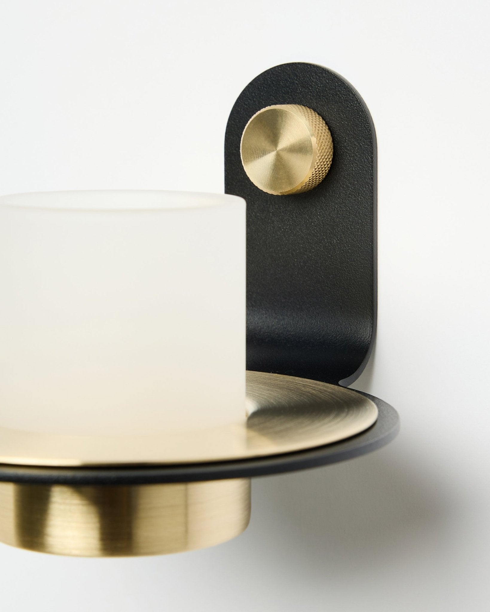 Le bougeoir Norr de WoodUpp, en black et brass, est présenté monté avec des bougies LED sur un Panneau acoustique blanc.