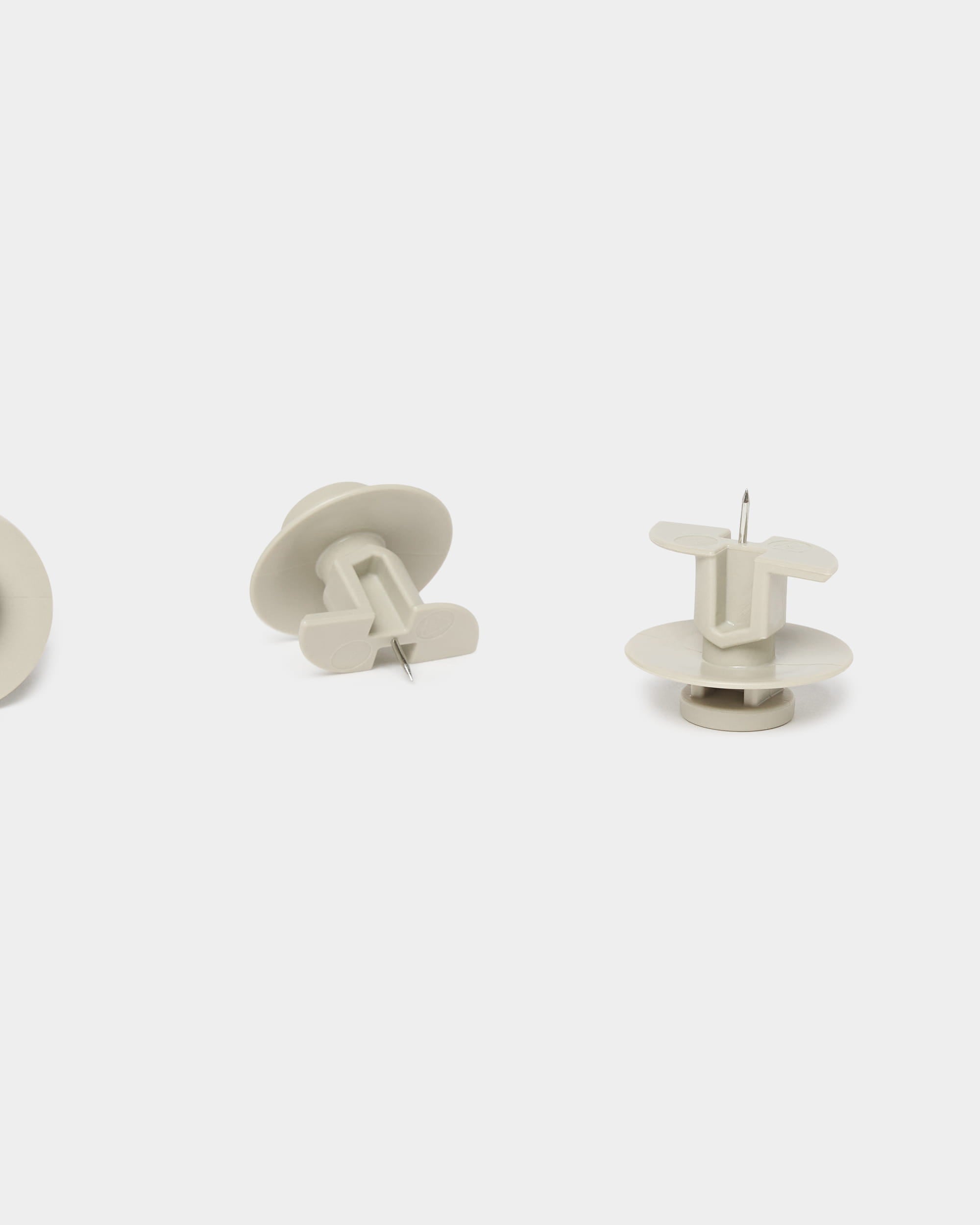 Lot de trois punaises WoodUpp Dupps beiges et dun outil, conçus pour les panneaux acoustiques Akupanel, présentés en position verticale et horizontale sur un fond blanc uni.