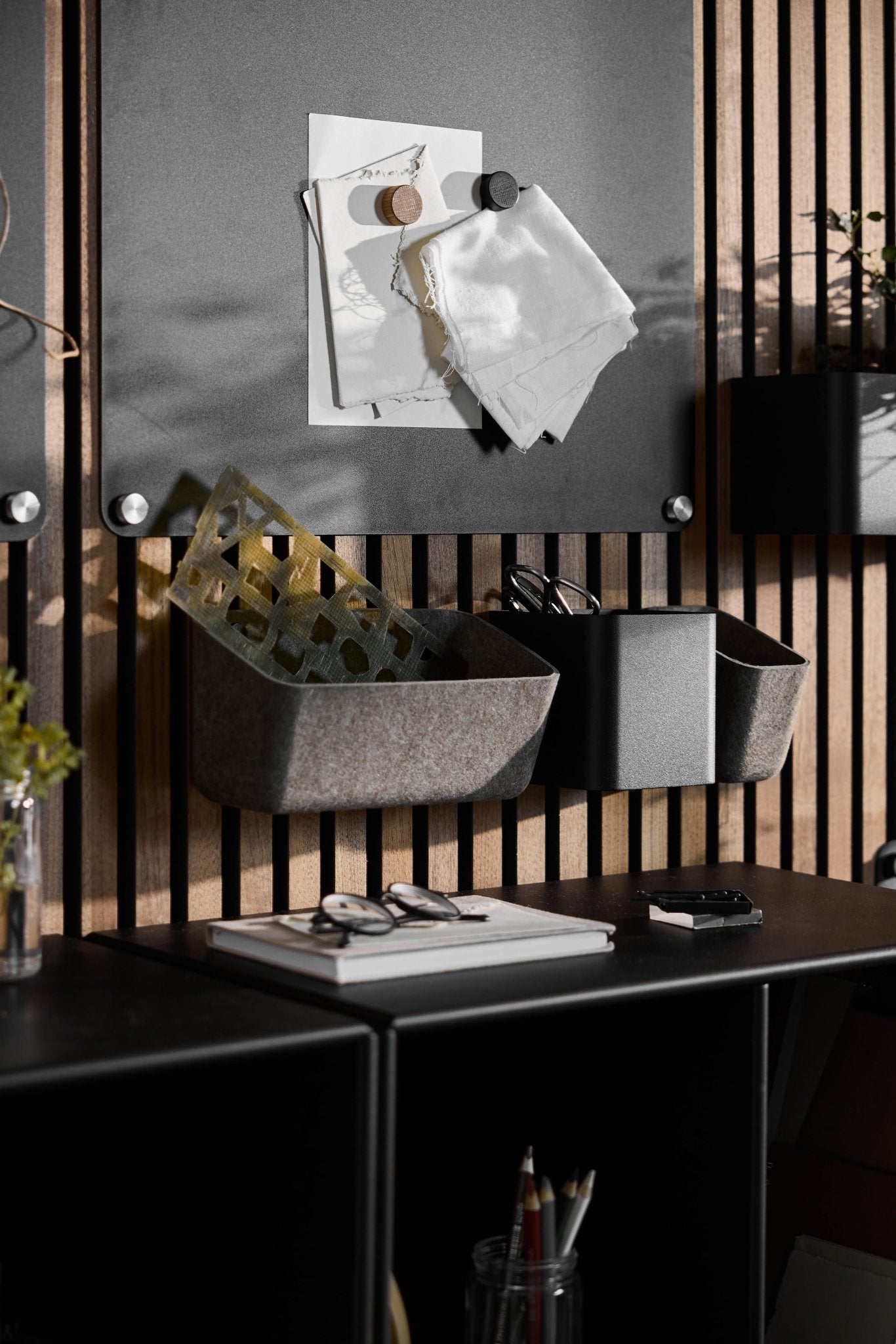 Les rangements en feutre WoodUpp Luva, dun gris foncé et chaleureux, permettent de ranger papiers et stylos au-dessus dun bureau, sintégrant parfaitement à un espace de travail nordique épuré et moderne.