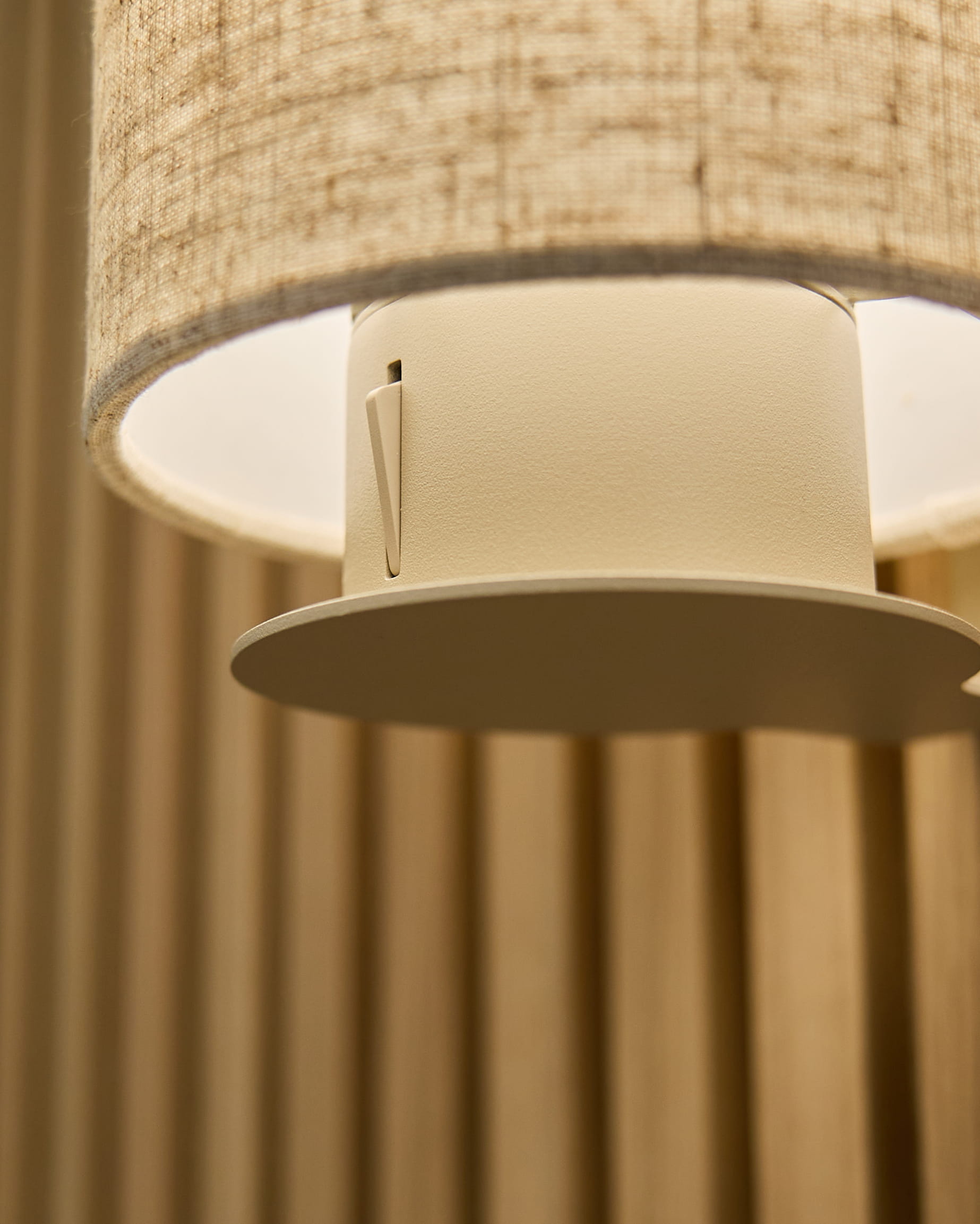 Gros plan sur l’applique Feya en Beige/Beige par WoodUpp, avec un abat-jour en lin-coton et un support cylindrique fixé sur des panneaux acoustiques vertical beige.