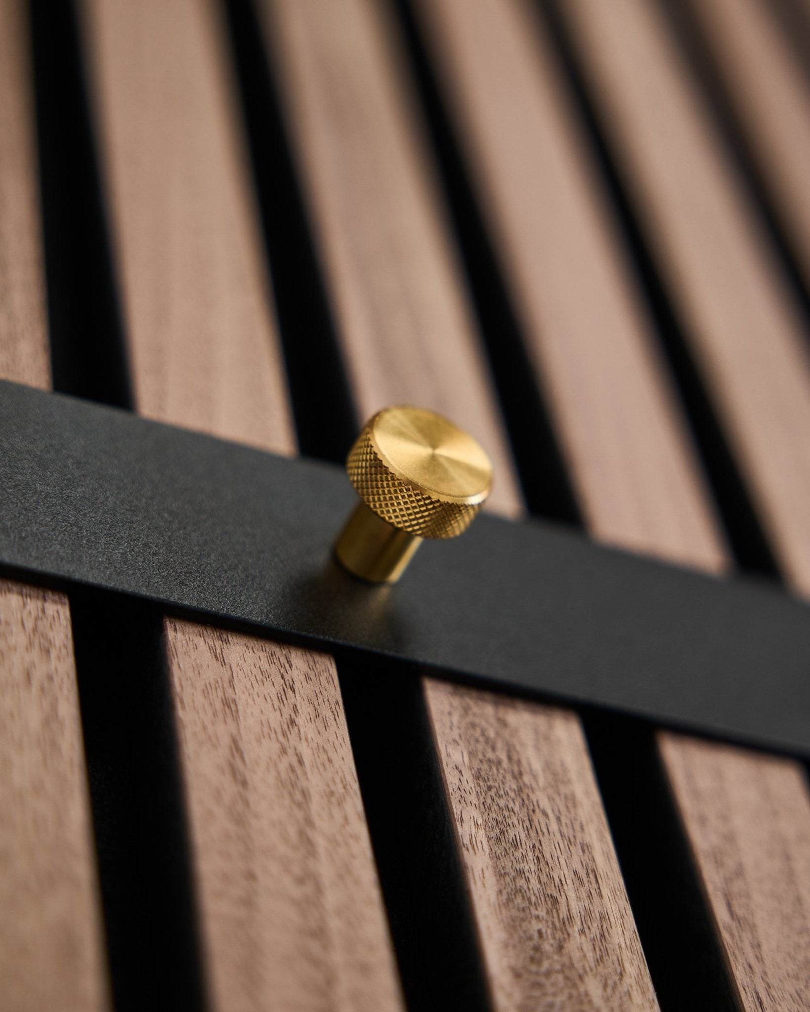 Le porte-manteau mural WoodUpp Norr comprend sept crochets black avec des embouts brass, montés sur un panneau mural à lattes brown, pensé comme un accessoire nordique pour Akupanel.