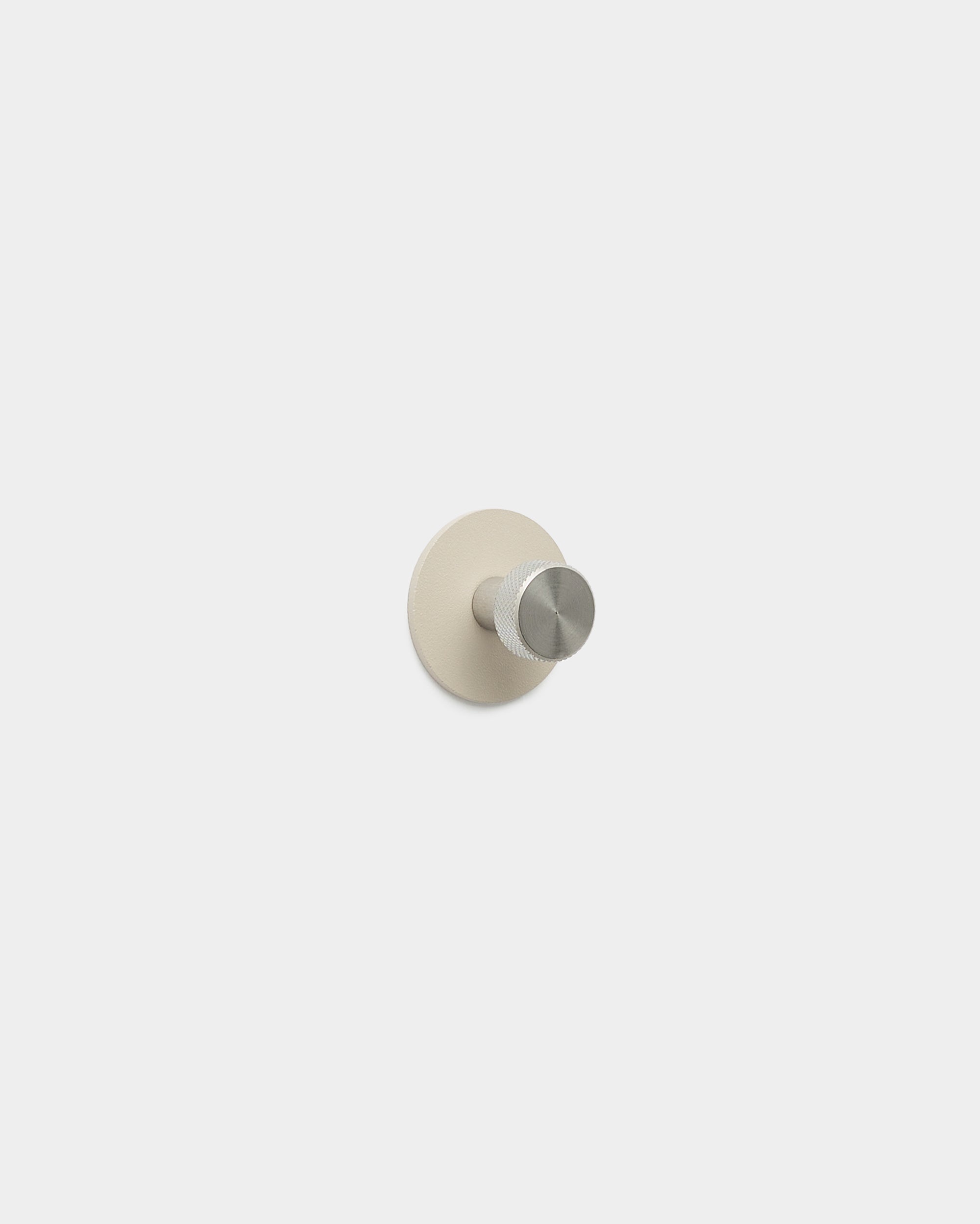 Patère WoodUpp Norr en beige et acier inoxydable steel, avec un crochet minimaliste et une base ronde, fabriquée en steel thermolaqué, issue de la collection d’accessoires WoodUpp.