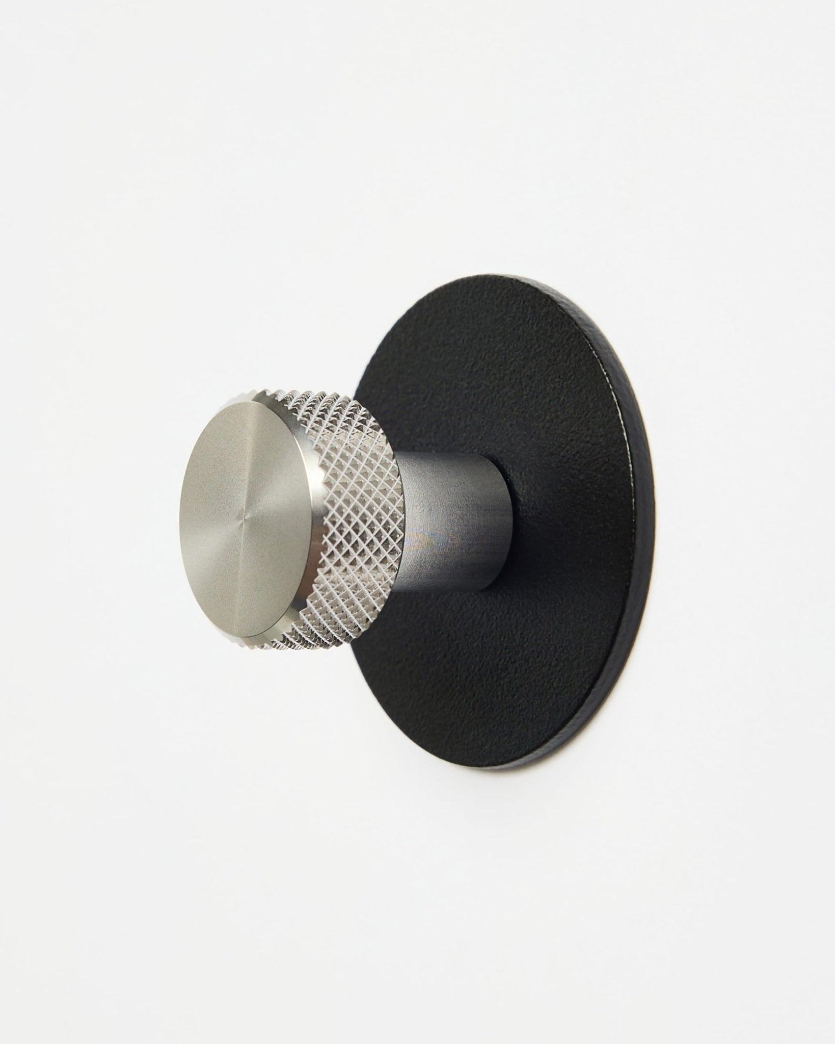 WoodUpp Norr | Coat Hook X1 en black et acier inoxydable steel, installé sur un mur blanc uni, conçu comme accessoire de la collection CREATE pour les systèmes Akupanel.