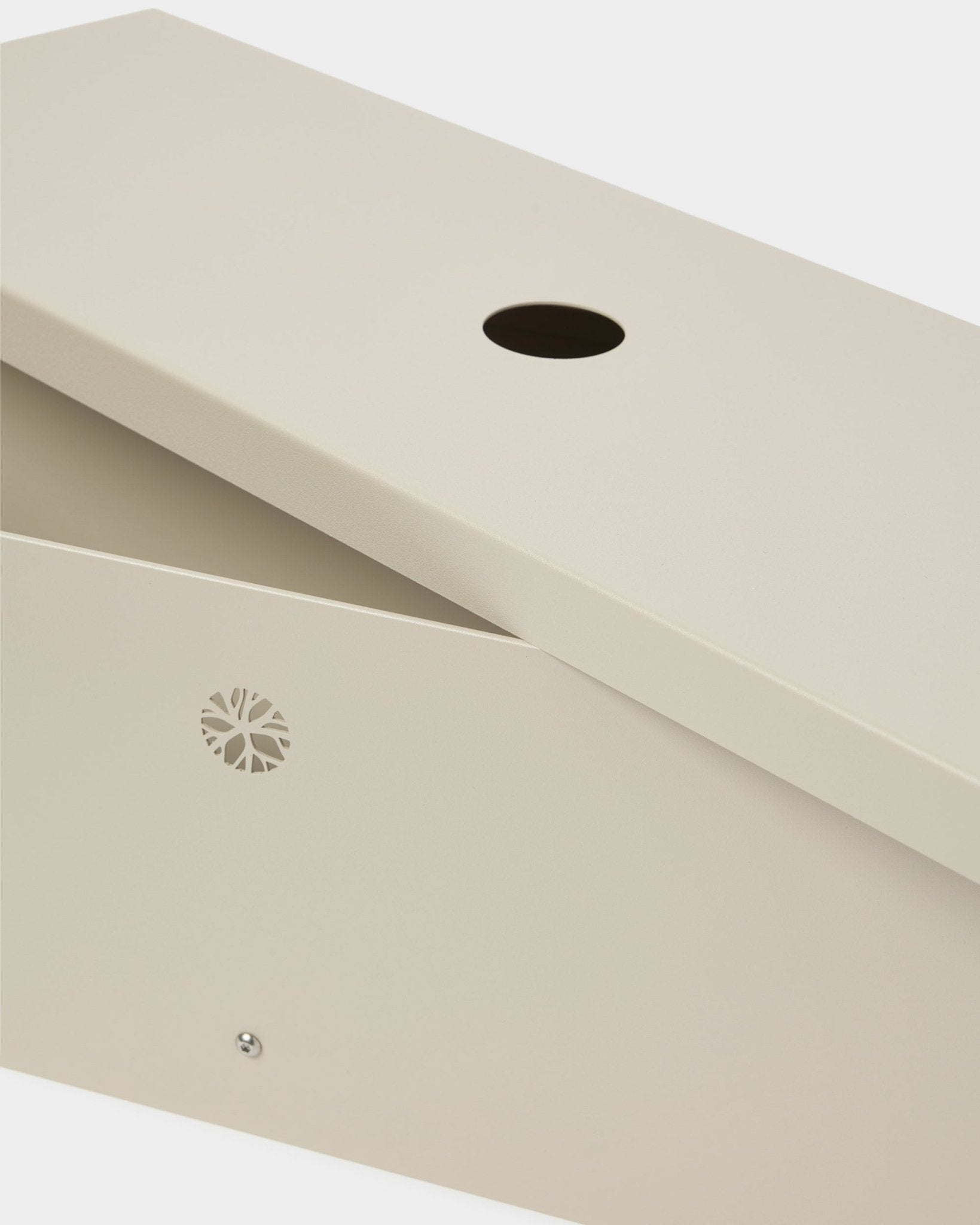 Le Nell | Metal Box / BM2, Beige de WoodUpp, fabriqué en steel thermolaqué, avec un couvercle incliné, une ouverture circulaire et un emblème discret sur le côté.