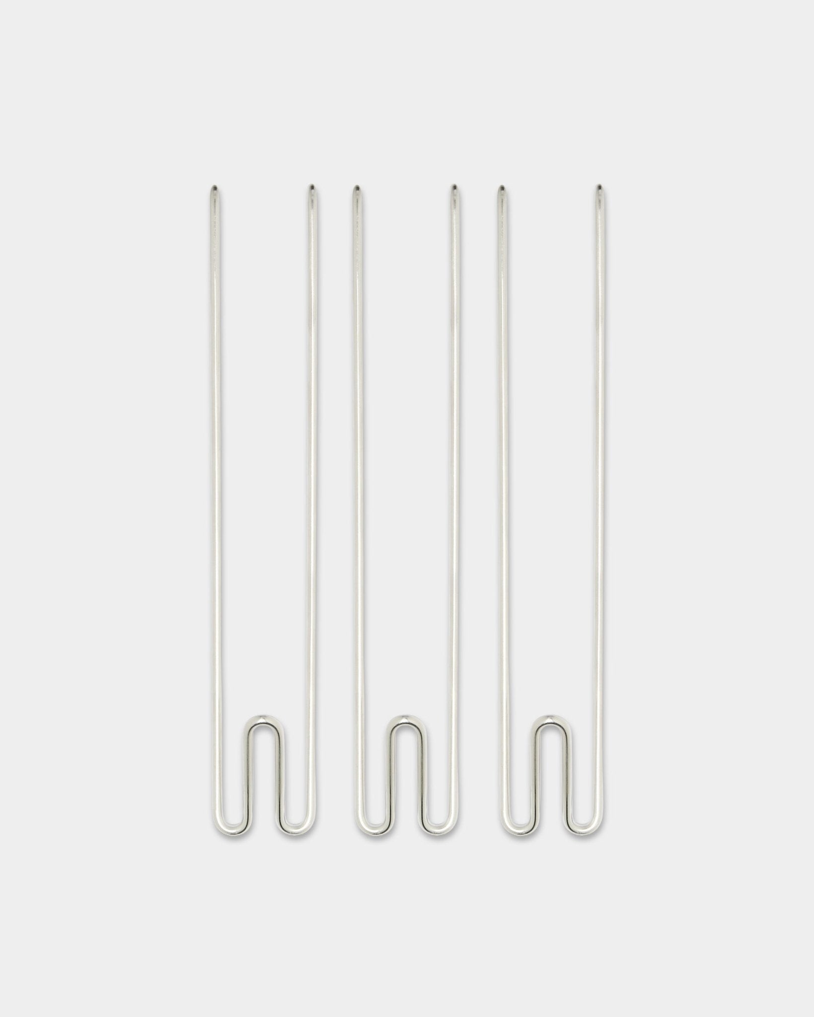 Trois accessoires Alva Wire Hook / BM1 de WoodUpp, longs crochets en acier inoxydable steel disposés verticalement sur un fond blanc uni.