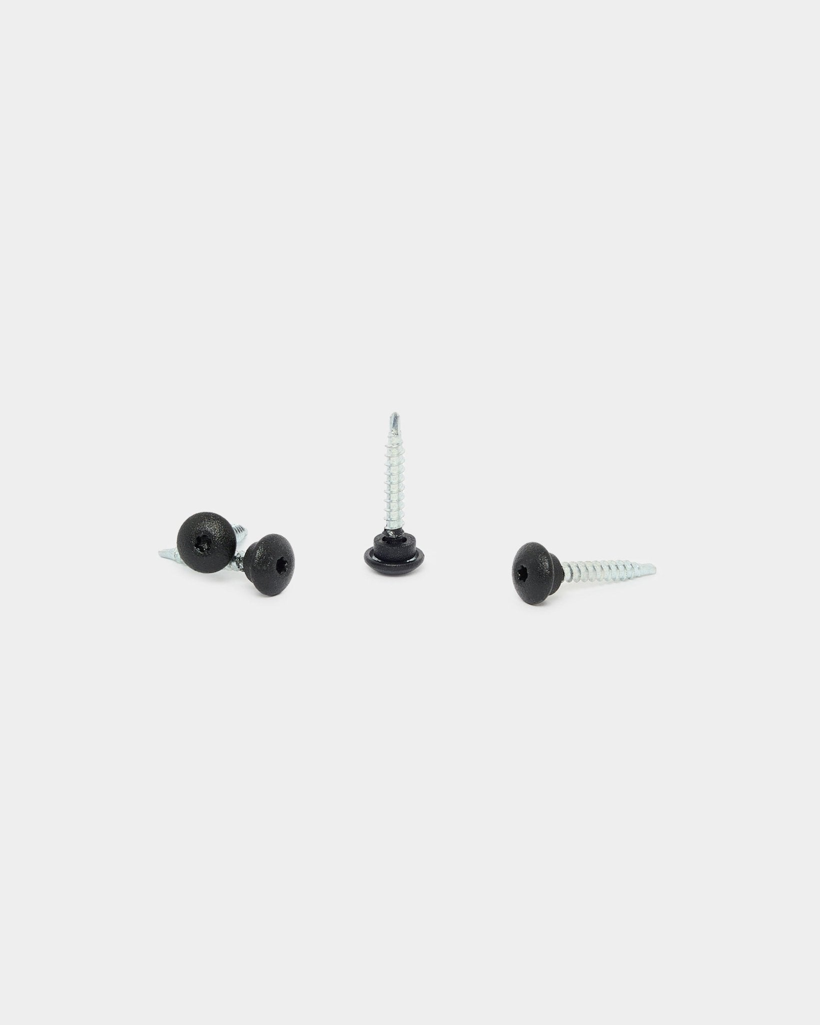 Trois vis frontales WoodUpp black 4.8x35 avec rondelles Ø9.5, conçues pour les panneaux acoustiques Akupanel, sur fond blanc : une à la verticale, deux couchées.