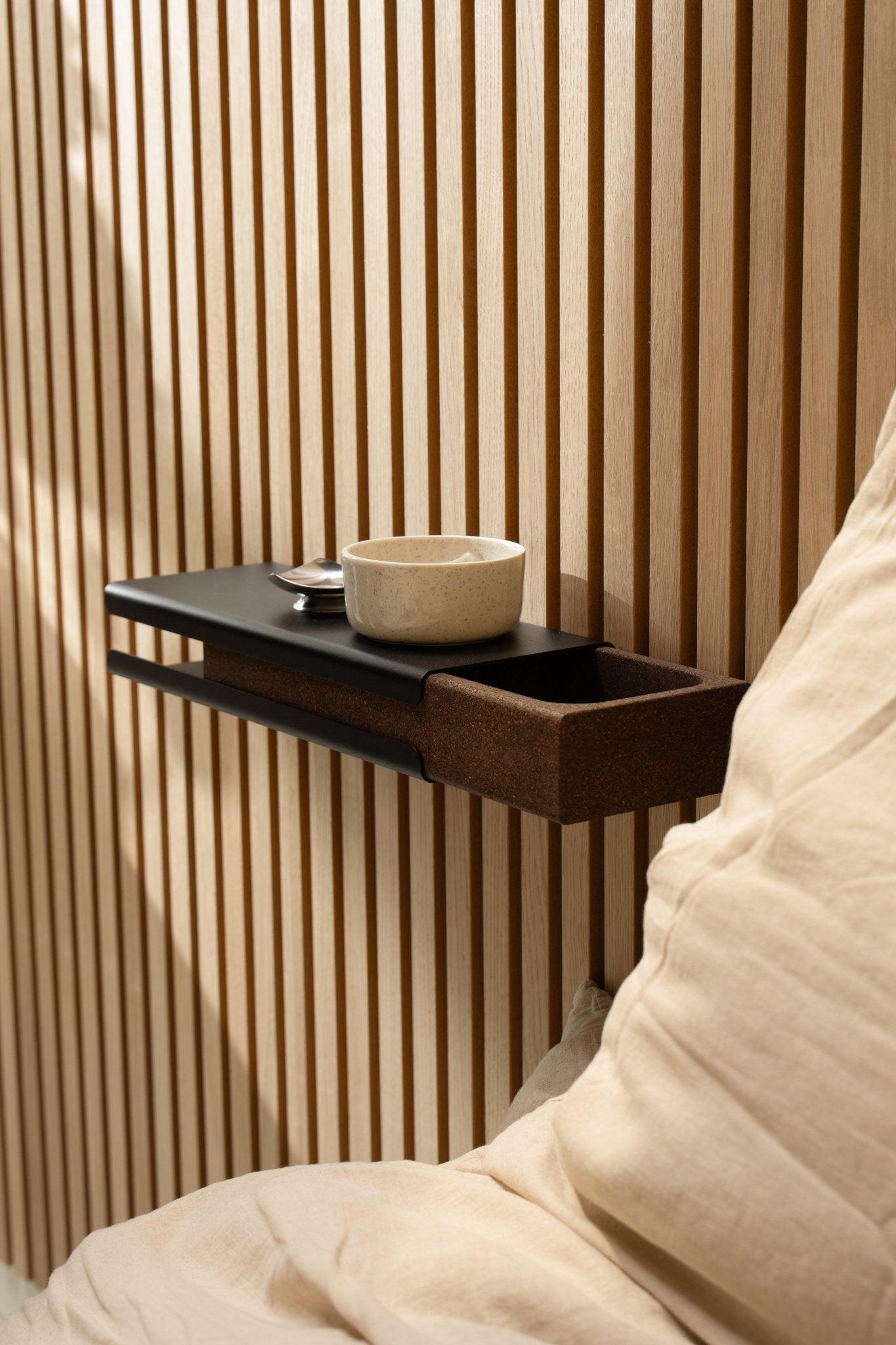 Étagère murale minimaliste avec un bol en céramique et WoodUpp Norr Key Tray à côté d’un coussin beige et de Akupanel Panneau acoustique, éclairée par une douce lumière naturelle.