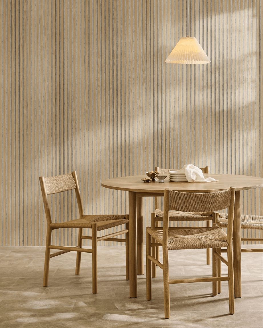 Salle à manger minimaliste avec une table ronde en bois, des chaises tressées, une suspension et un panneau acoustique en bois WoodUpp Akupanel en chêne classique avec feutre grey.