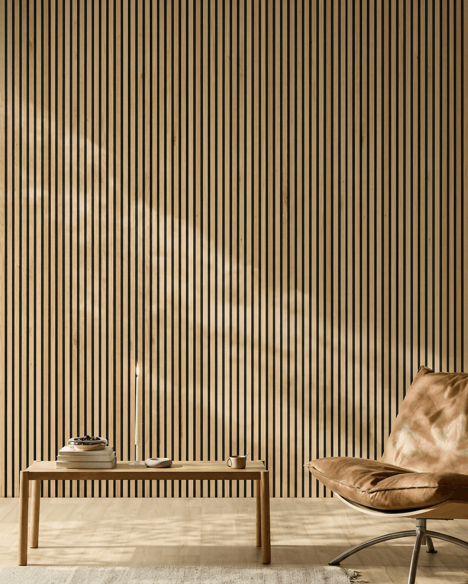 La lumière du soleil éclaire une pièce moderne avec un Akupanel WoodUpp Panneau acoustique en Rustic Natural Oak sur le mur, aux côtés d’un fauteuil en cuir fauve et d’un banc minimaliste.