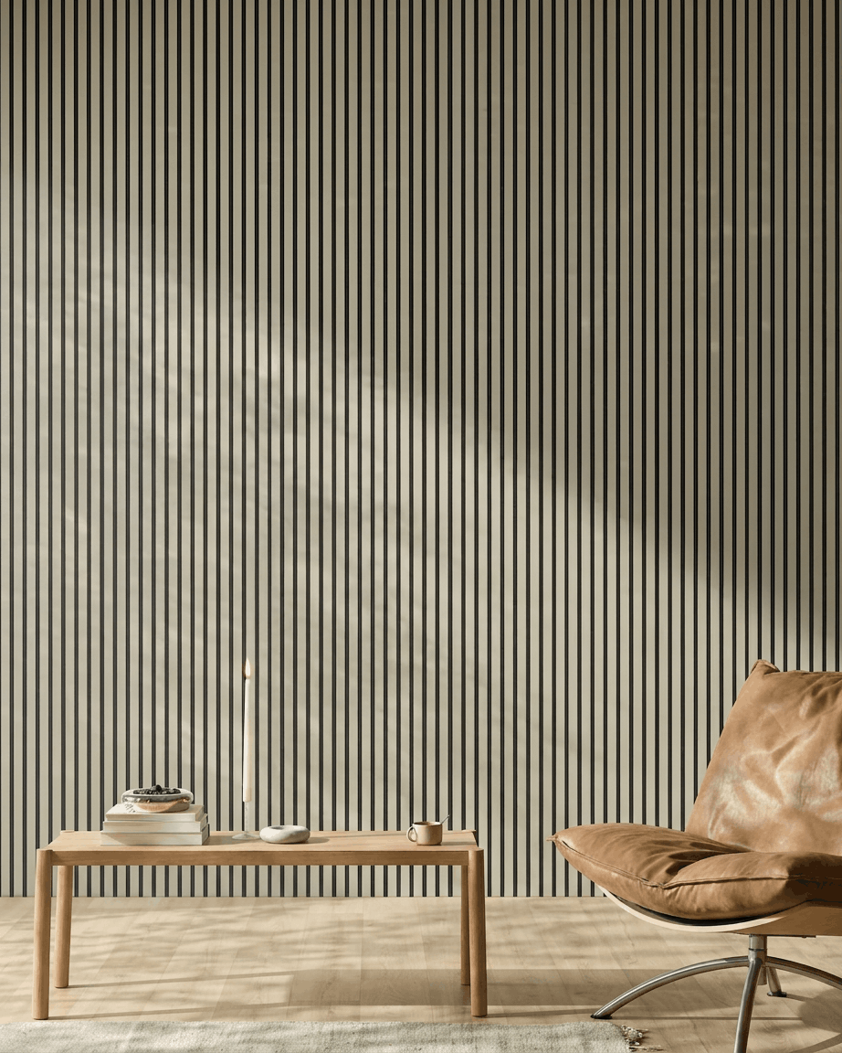 Pièce minimaliste avec un fauteuil en cuir fauve, un banc en bois, des livres, une bougie, et le Panneau acoustique WoodUpp Akupanel Stone/Black Felt (240x60 cm) sur le mur.
