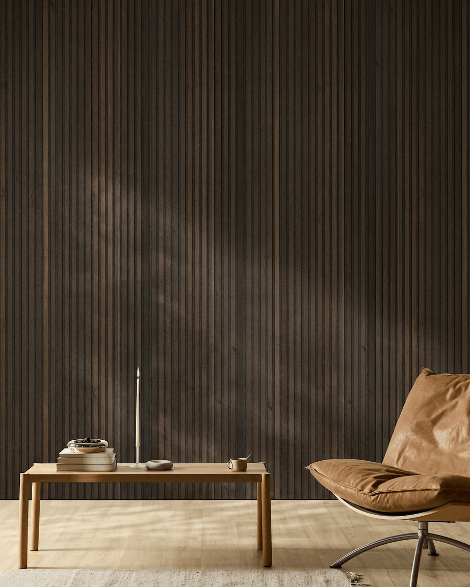 Pièce nordique minimaliste avec fauteuil en cuir fauve, table en bois, bougie et tasse, devant un mur WoodUpp Akupanel Natural Wood Rustic Smoked Oak Panneau acoustique.