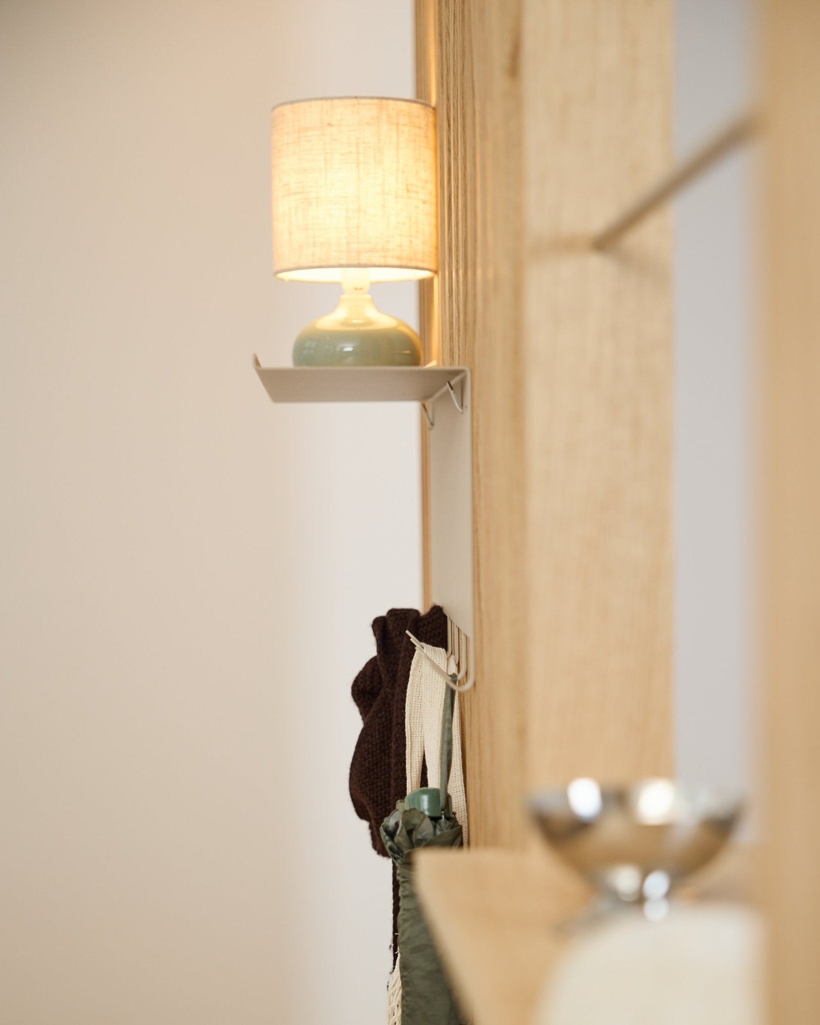 Un porte-manteau WoodUpp Nell BM1 beige (63,5 x 24 cm) se trouve sous une lampe de table small, à côté d’un mur en bois clair d’inspiration nordique Panneau acoustique.