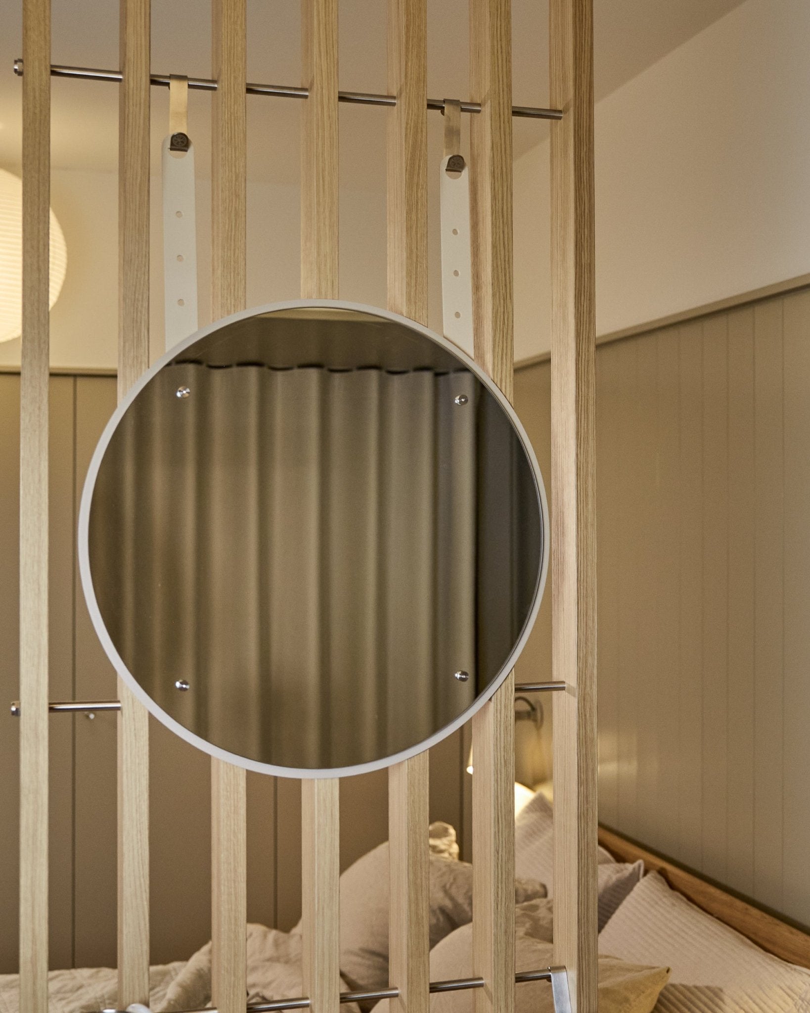 Miroir Vala BM1 rond et réglable en hauteur de WoodUpp, 54 cm de diamètre, monté sur un panneau acoustique à lattes de bois vertical, avec un éclairage doux aux tons neutres.