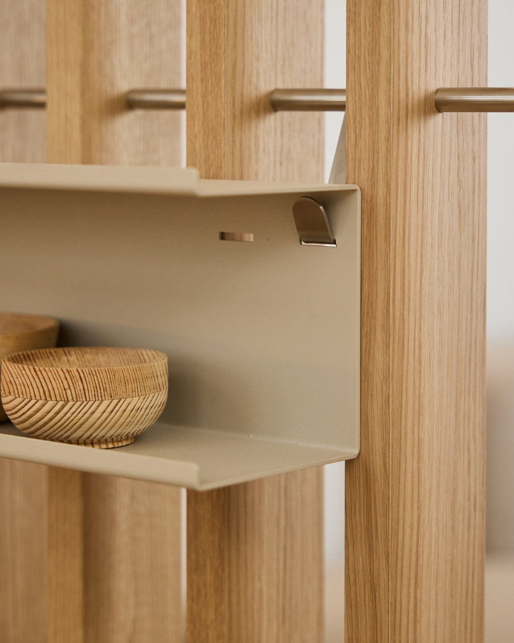 Gros plan sur l’étagère métallique double Nell de WoodUpp / BM1 en beige, 63,5 cm, avec des bols tressés et des lattes acoustiques nordiques en bois vertical, montées sur des tiges steel.